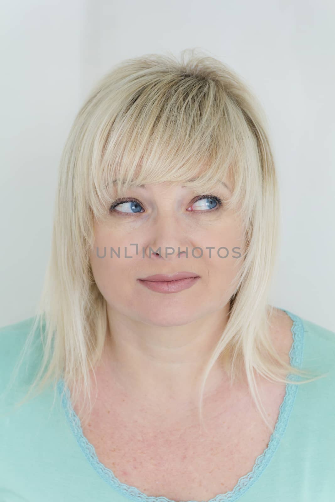 blond woman with blue eyes in green looking to left