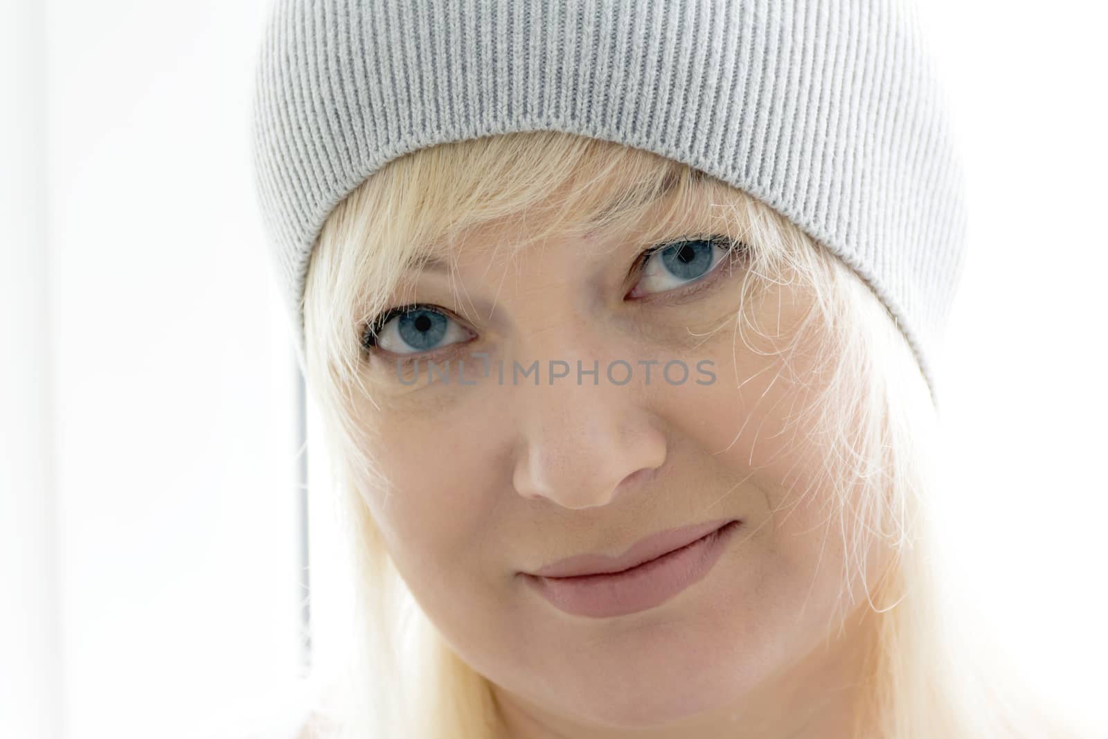 horizontal portrait of blond woman with blue eyes in grey hat
