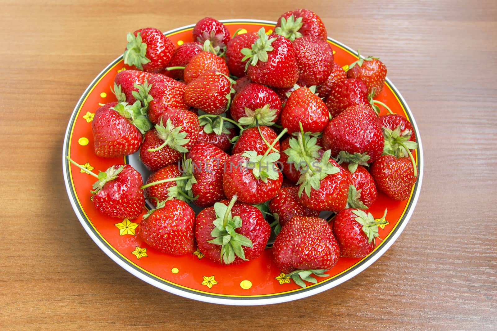 Photo of ripe juicy strawberry in a red plate