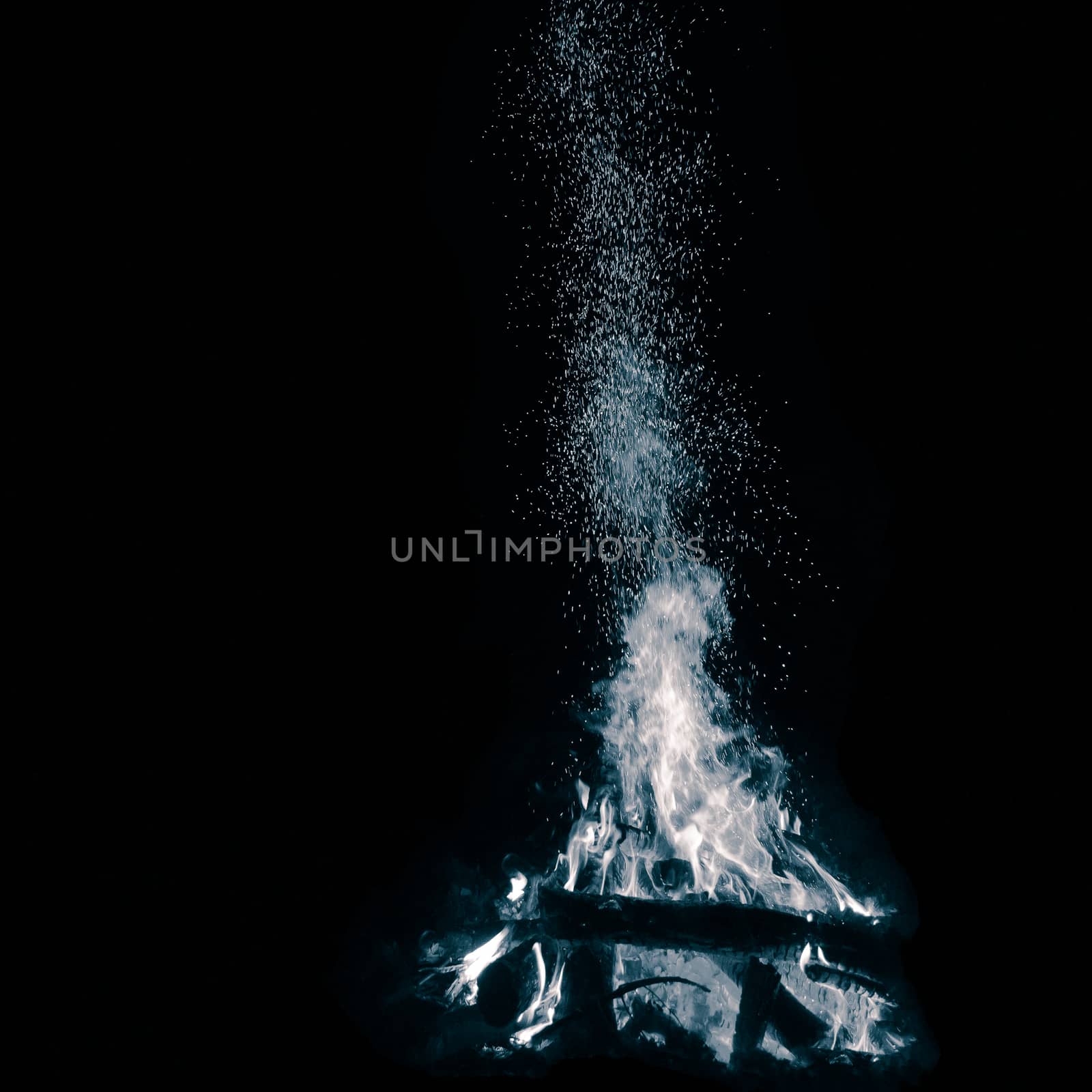 Blue bonfire with flying sparks isolated on black