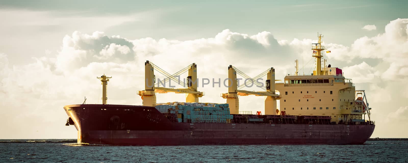 Red cargo ship moving entering the port of Riga