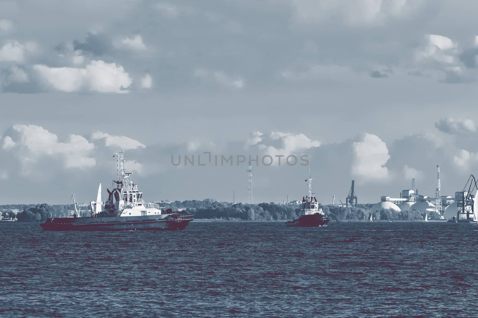 Two tug ships are accepting cargo vessel at Daugava river