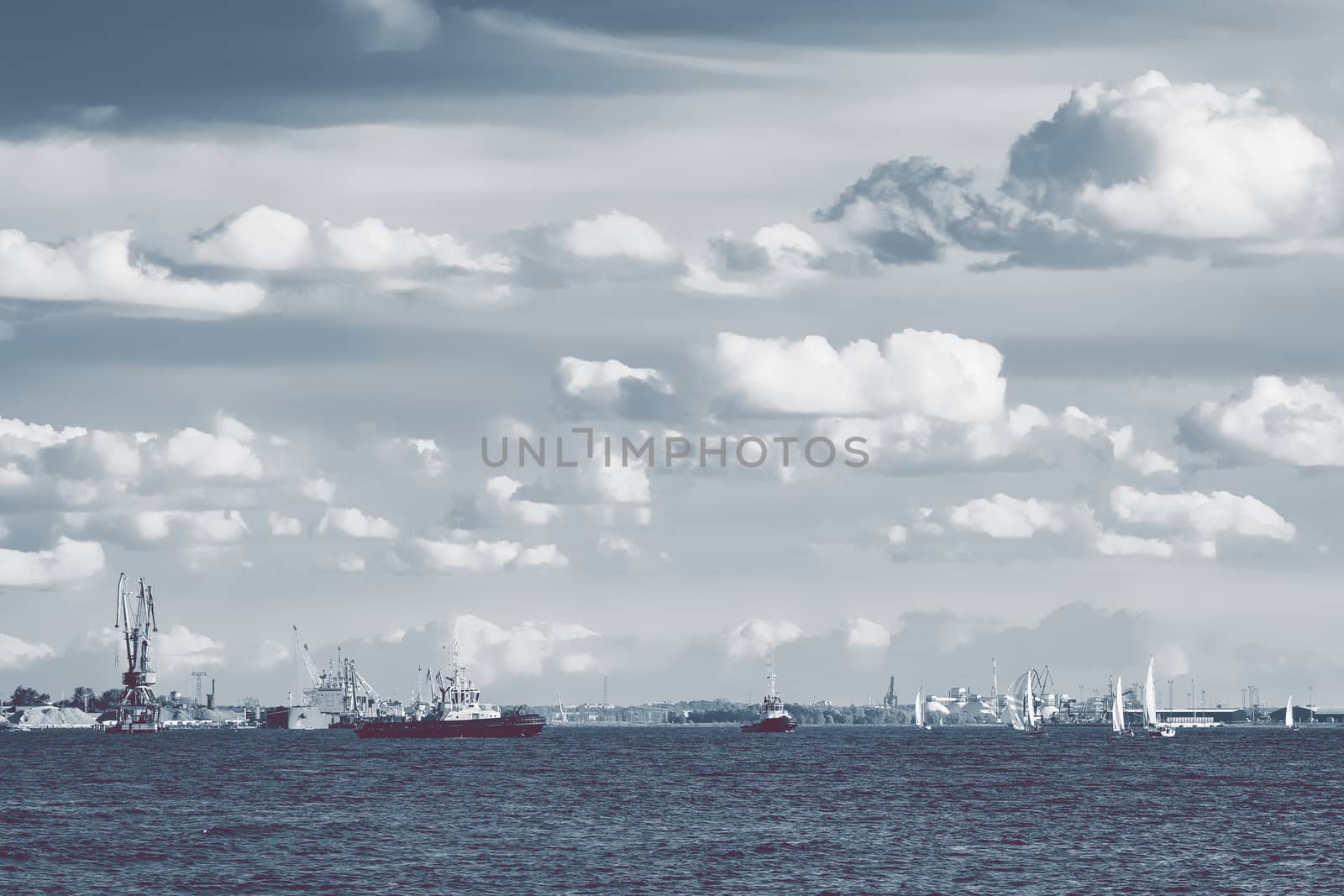 Tug ships and sailboats against cargo terminal in Riga