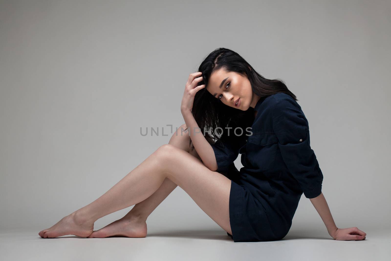 full body shot of beautiful black haired lady with a shirt, lying on the ground bare feet