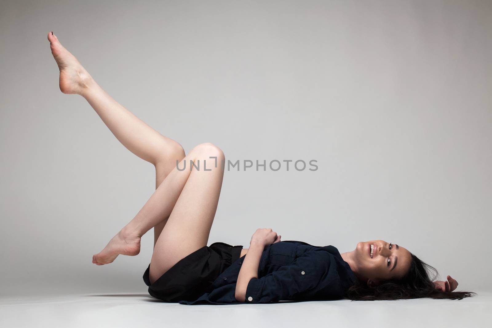 full body shot of beautiful black haired lady lying on the ground bare feet