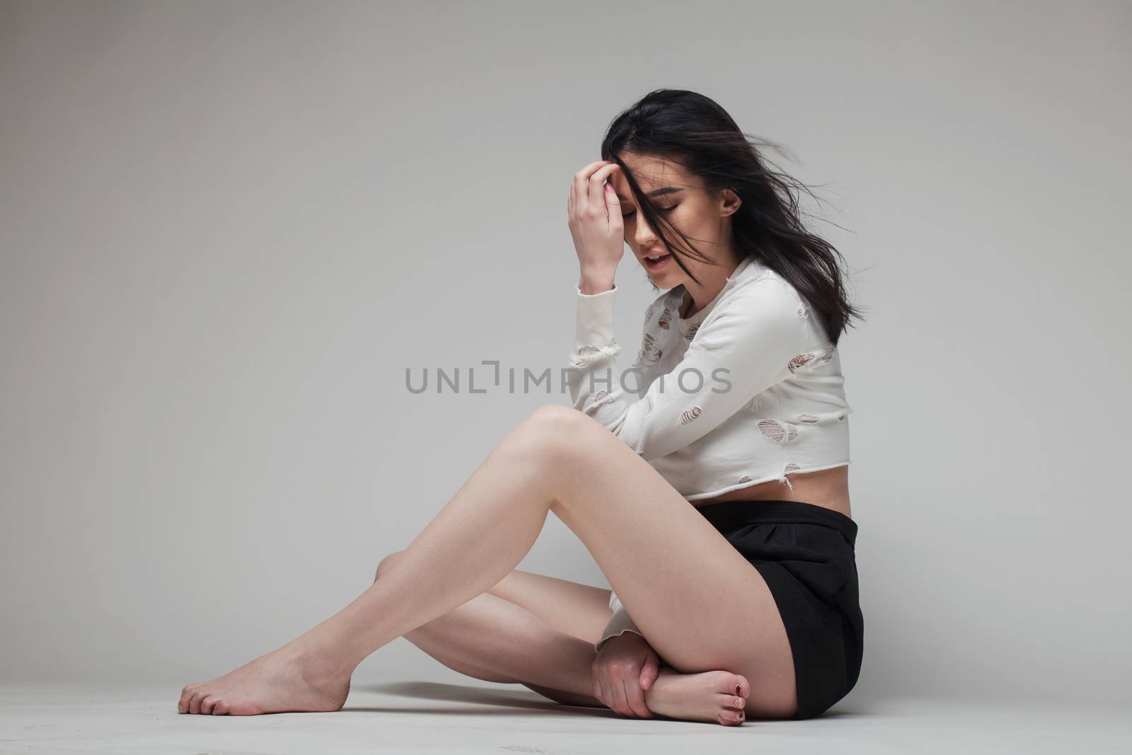 full body shot of beautiful black haired lady sitting on the ground bare feet