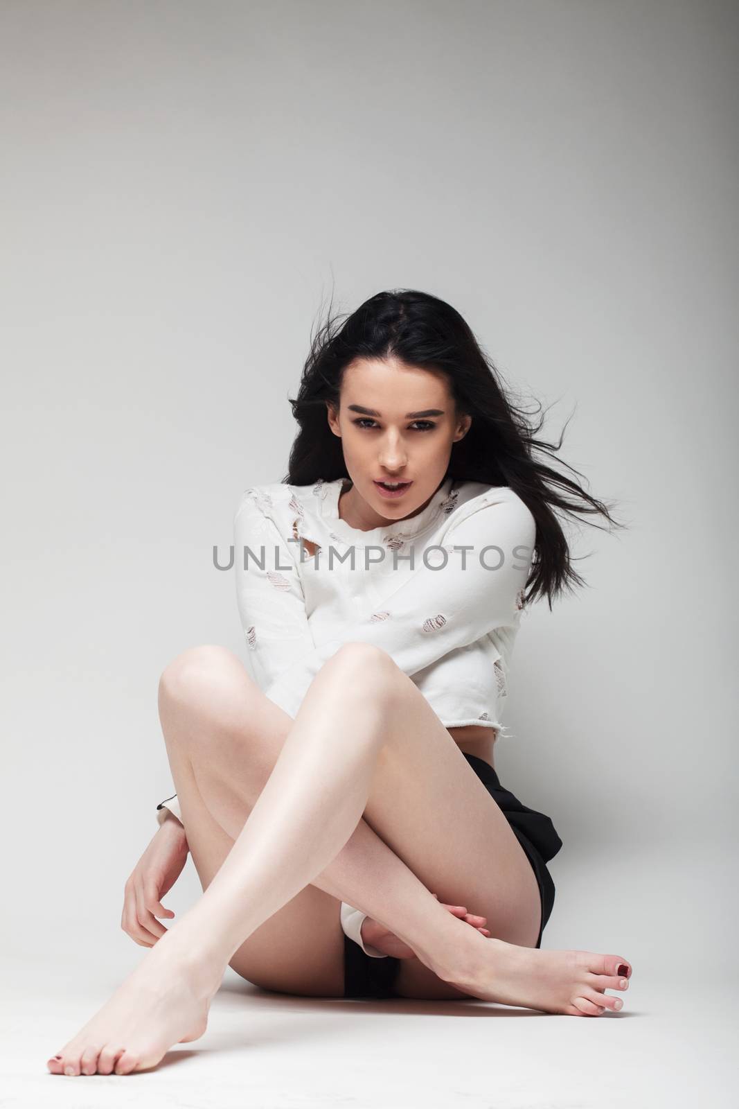 full body shot of beautiful black haired lady sitting on the ground bare feet