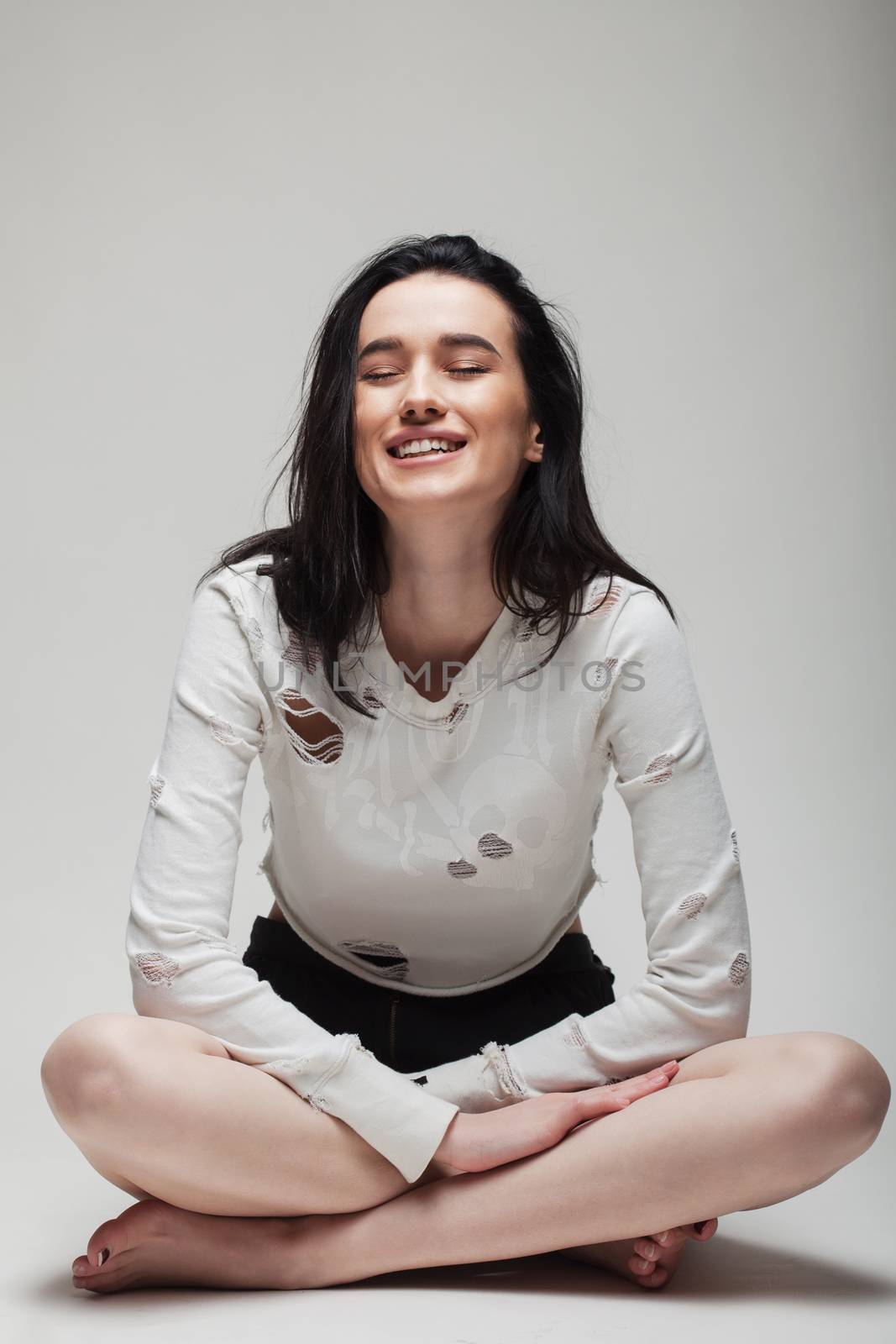 full body shot of beautiful black haired lady sitting on the ground bare feet