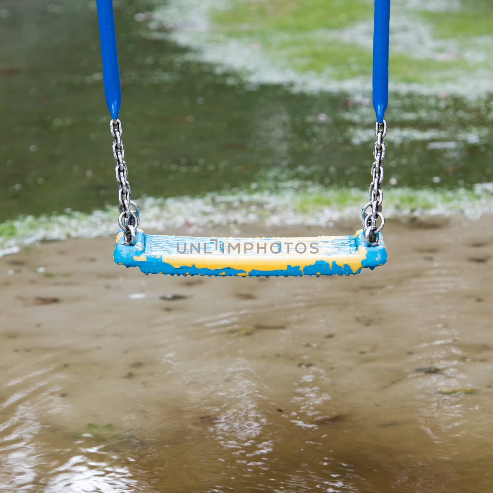 Old plastic swing hanging over a puddle