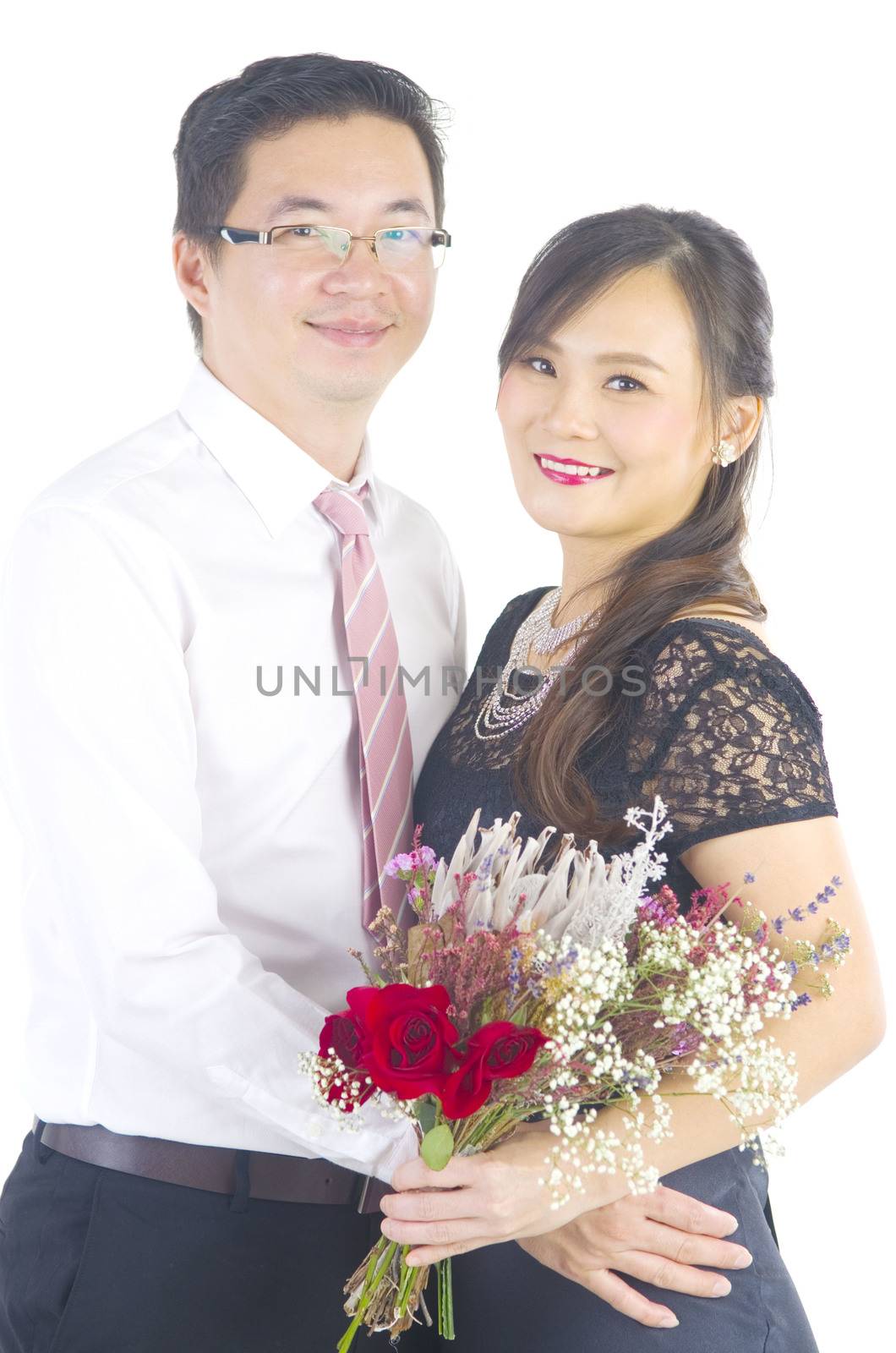 Portrait of young elegant enamoured just married groom and bride embracing at Wedding on white background