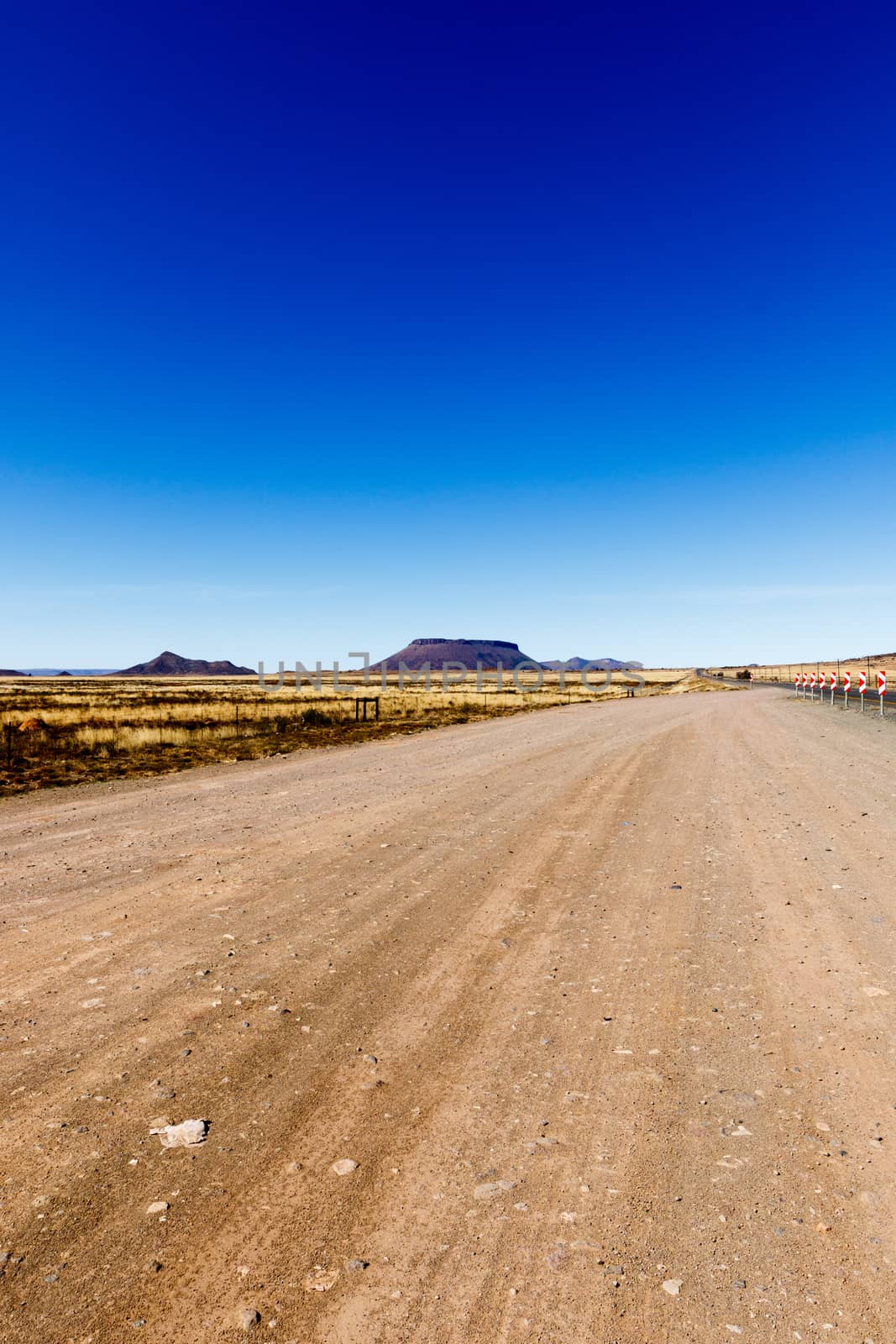 Dirt road with the view of the mountains on the side by markdescande