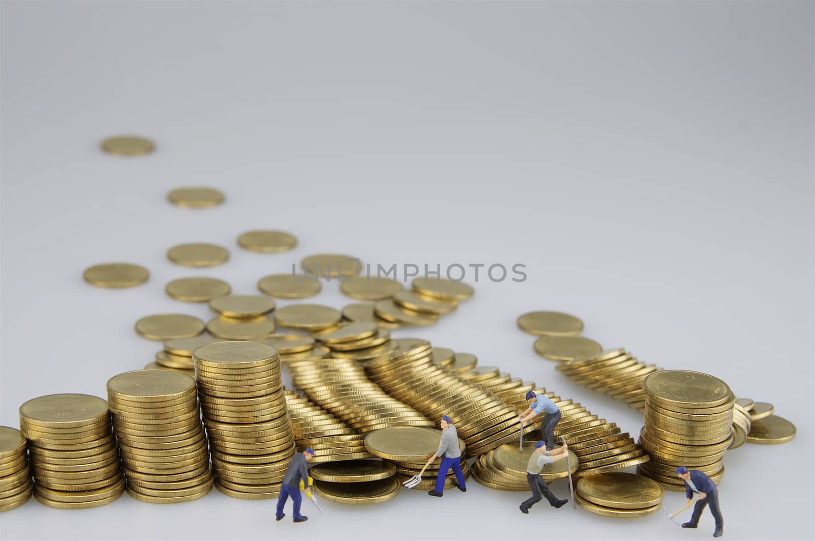 Miniature people are destroyed pile of gold coins on white background.