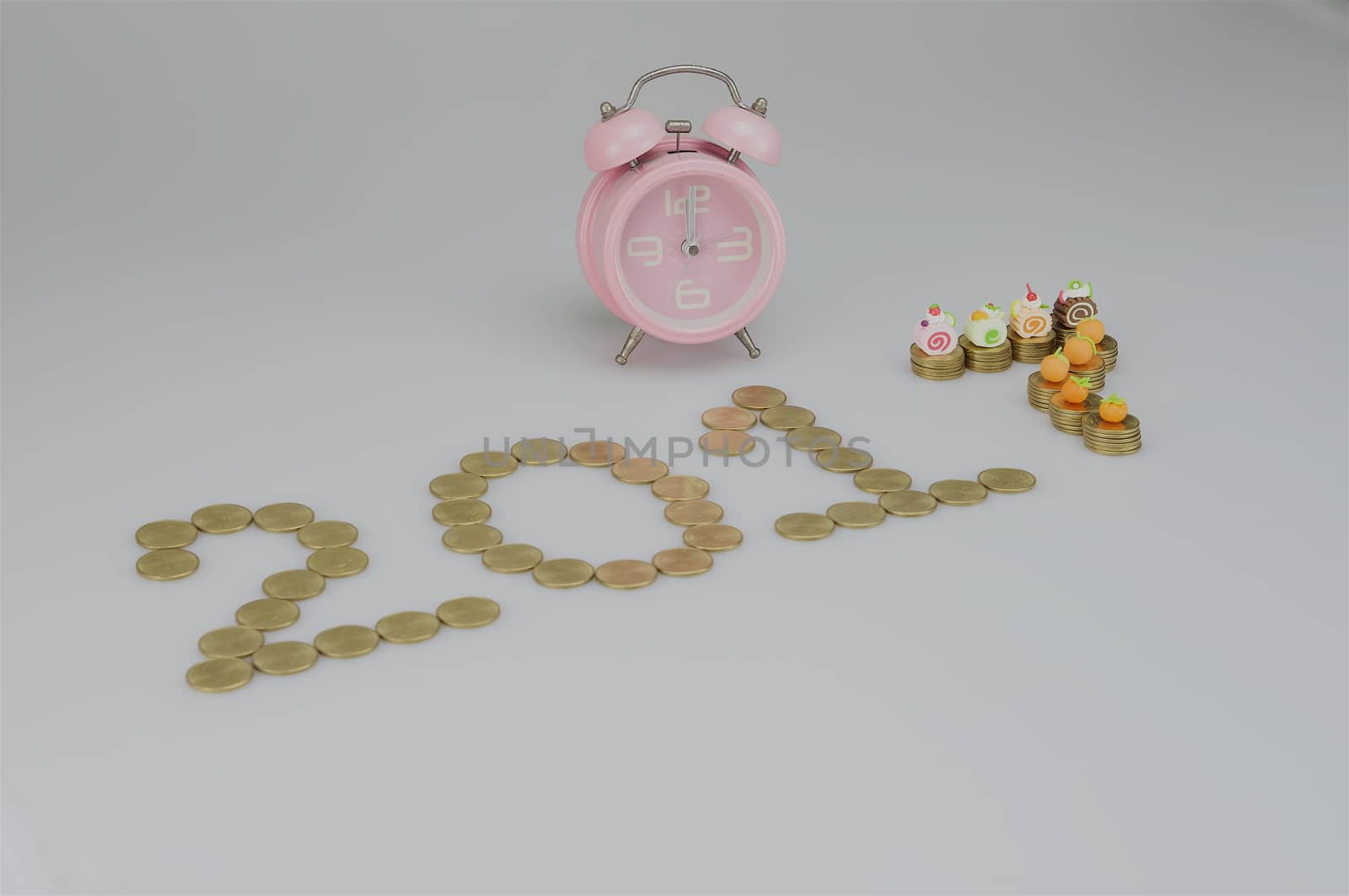 Pink old style alarm clock and pile of gold coins as 2017.