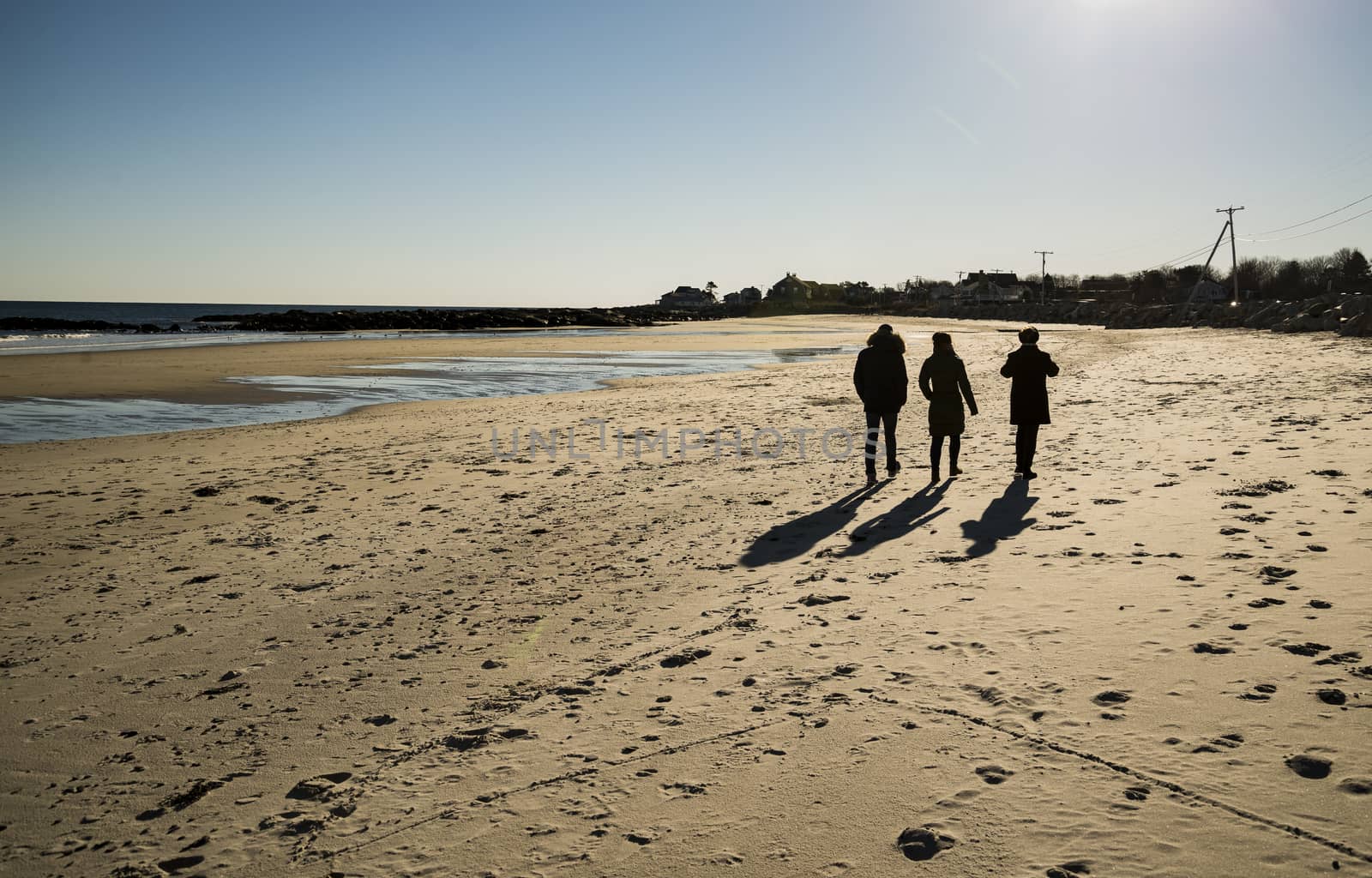 Friends walking at sunset on the beach in Maine, USA