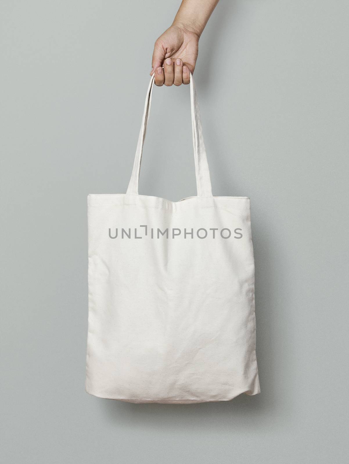 female hand holding a cloth bag on a gray background