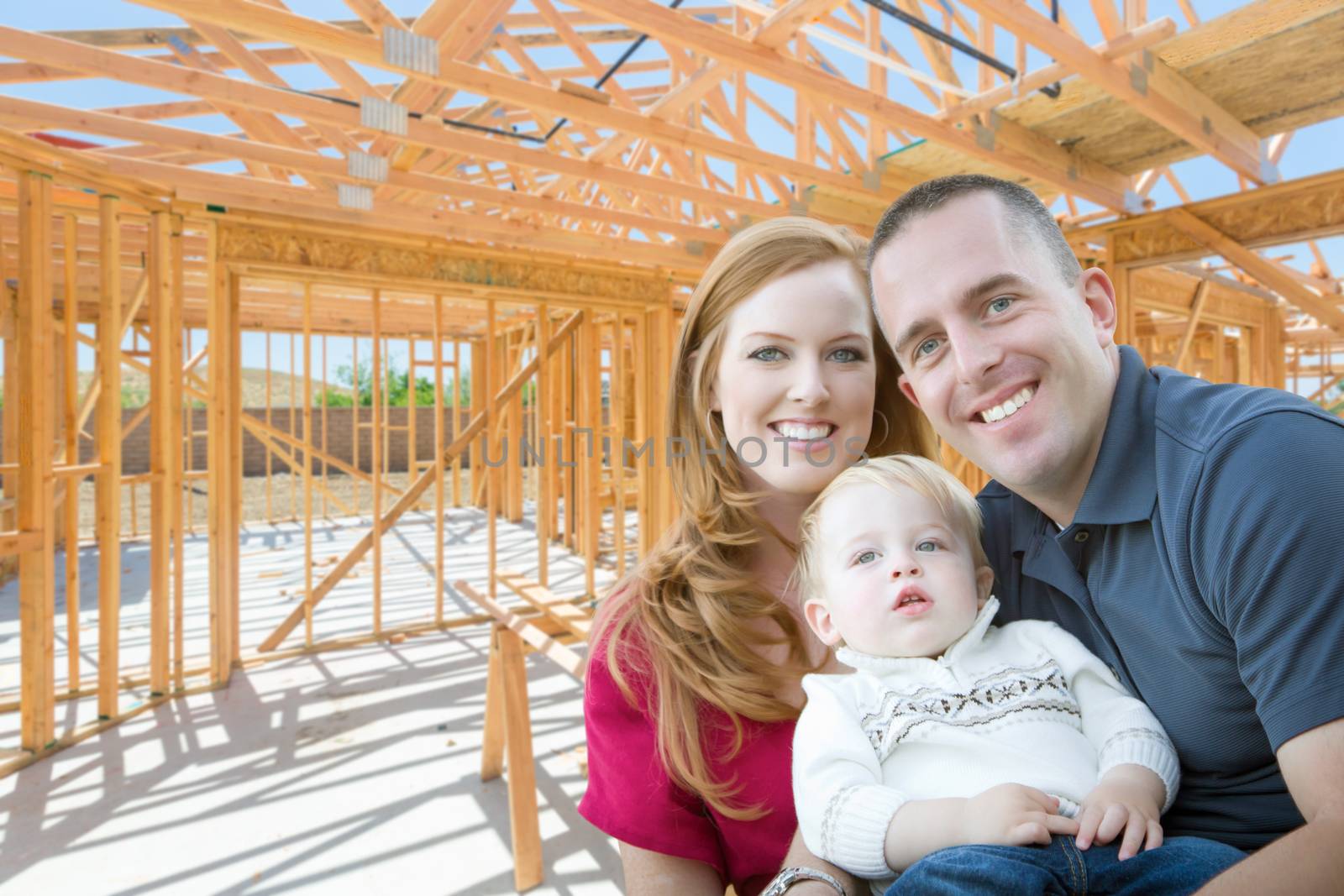 Young Military Family Inside The Framing of Their New Home at Construction Site. by Feverpitched