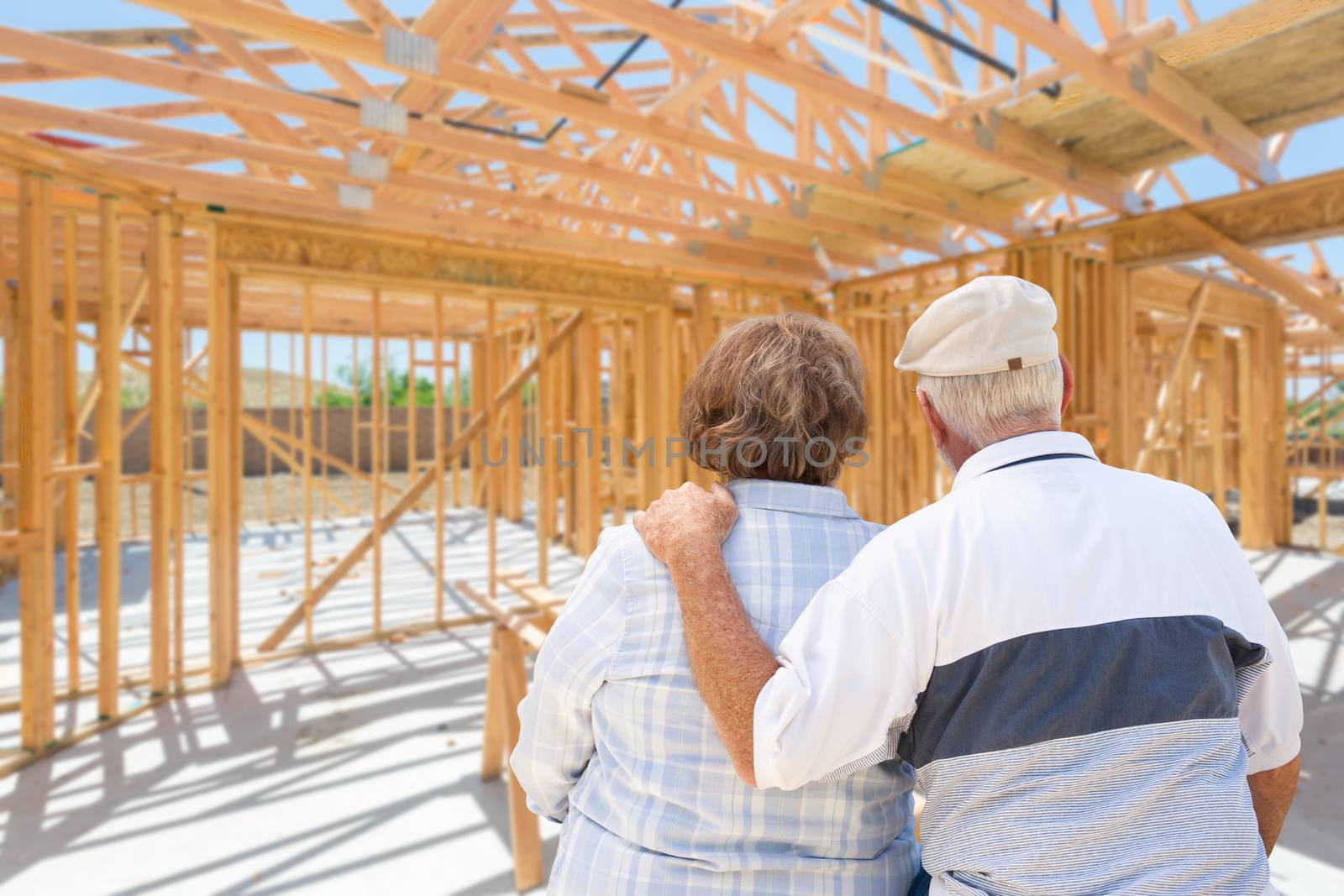Senior Couple On Site Inside Their New Home Construction Framing.