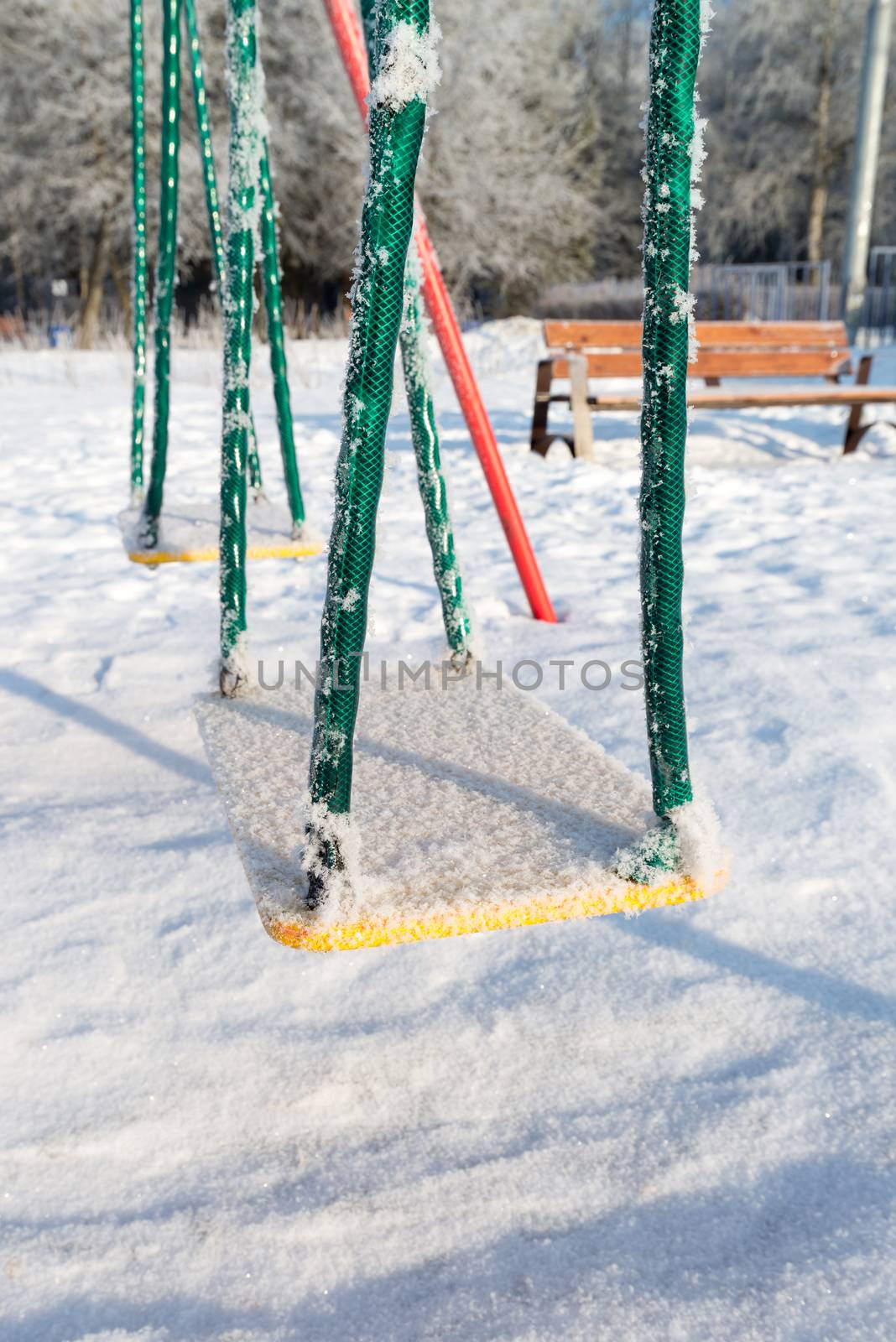 snow covered swing and slide at a playground in winter