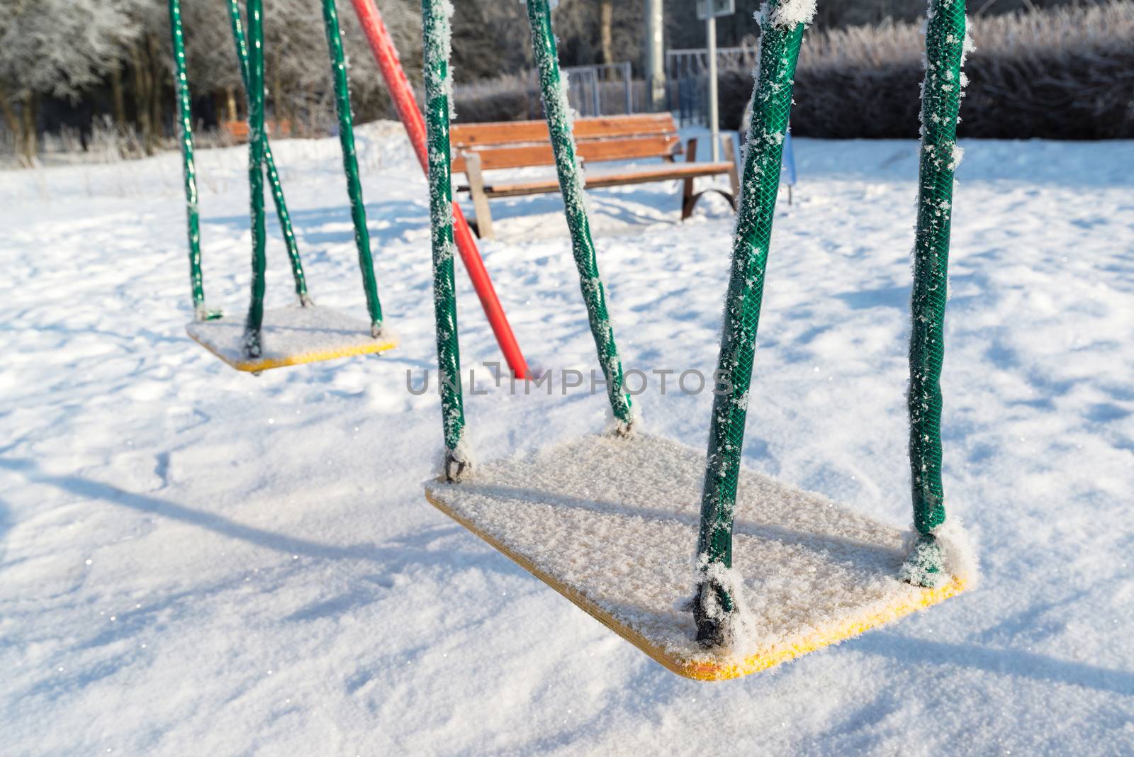 snow covered swing and slide at a playground in winter