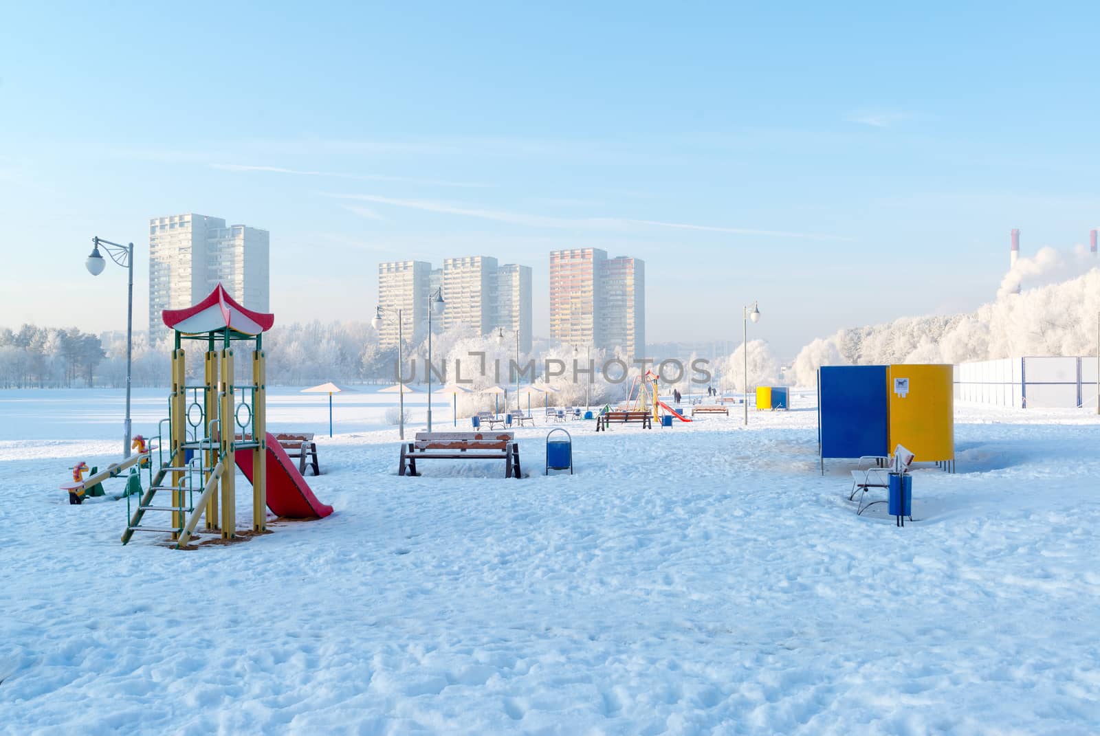 snow covered swing and slide at playground in winter by olgavolodina