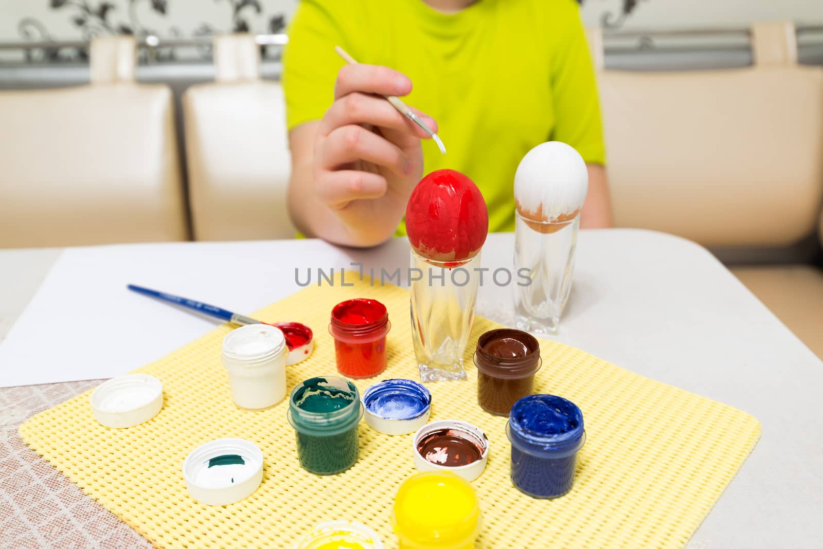 boy paints  and brush easter eggs by olgavolodina