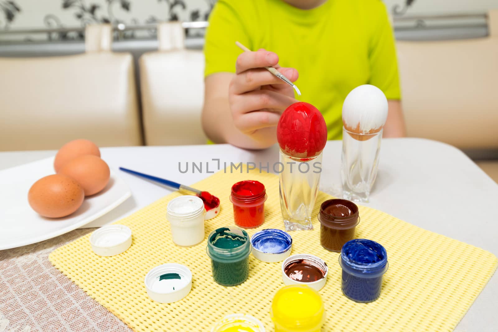 boy paints paints and a brush easter eggs