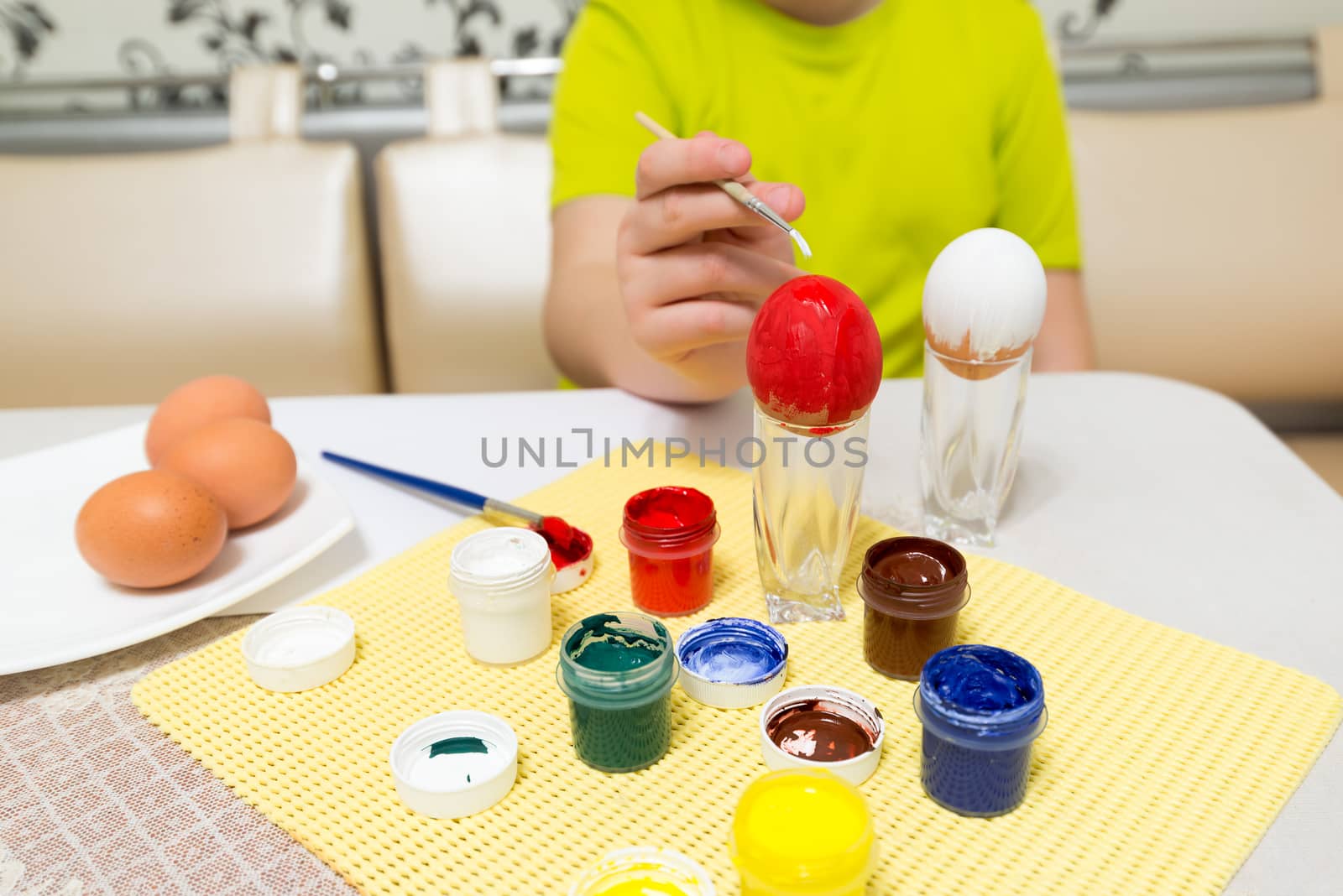 boy paints  and brush easter eggs by olgavolodina