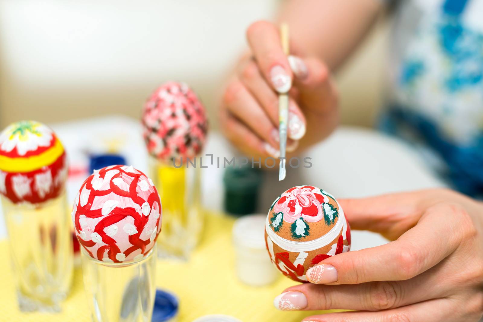 Woman paints the Easter eggs with a brush