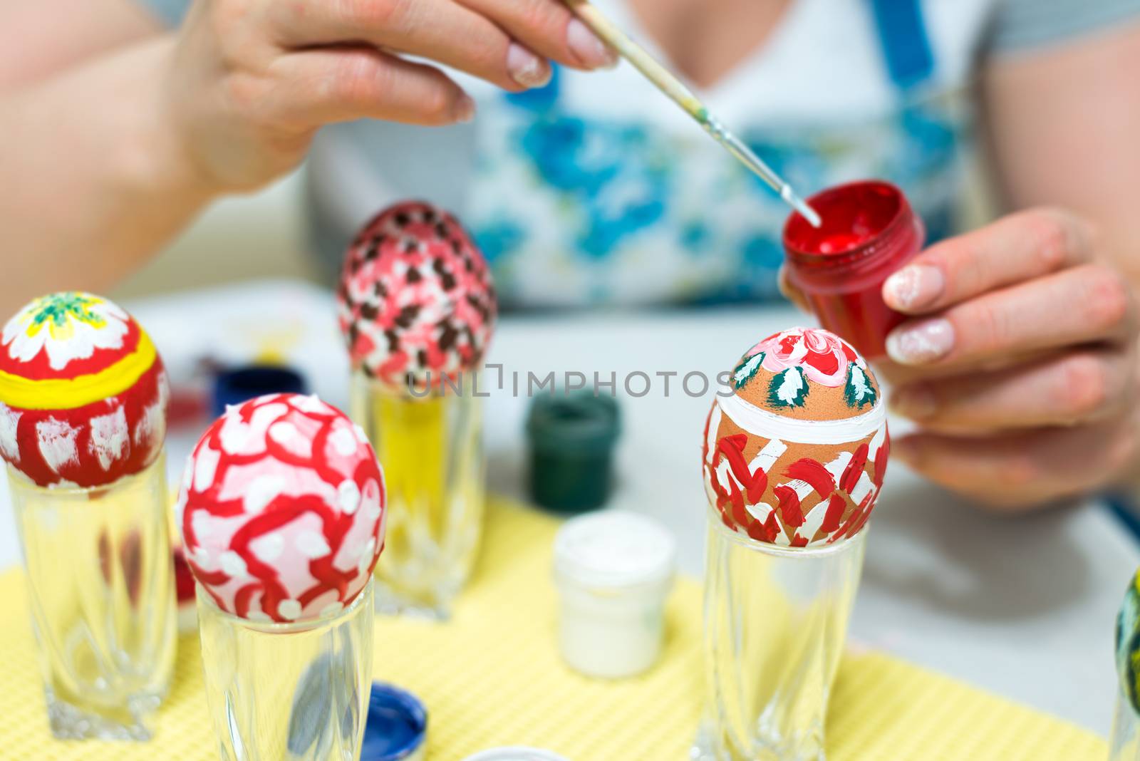 Woman paints the Easter eggs with brush by olgavolodina