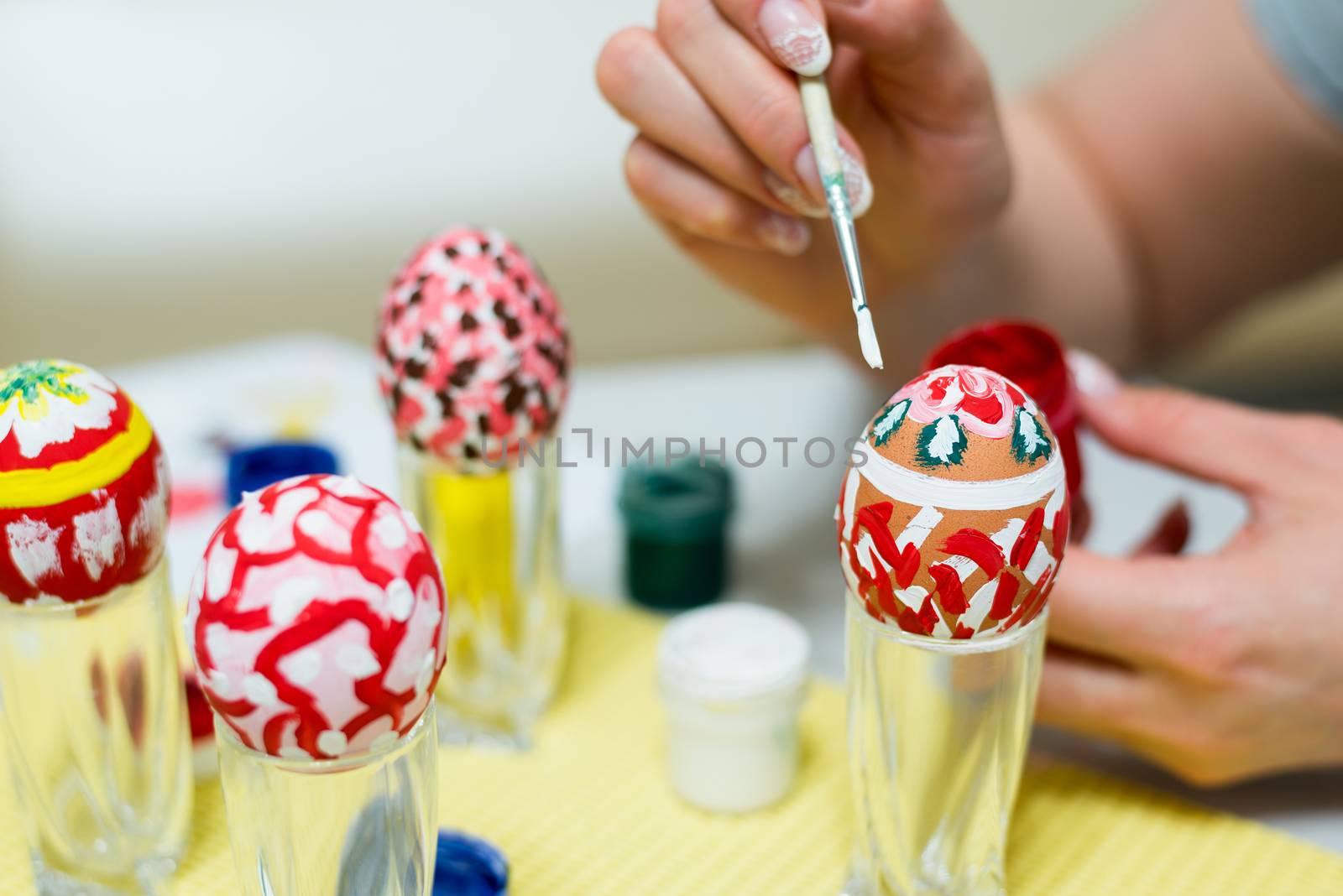 Woman paints the Easter eggs with brush by olgavolodina