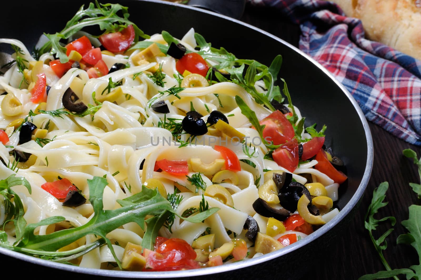 Pasta with crushed olives and cherry tomatoes, arugula. Horizontal shot.