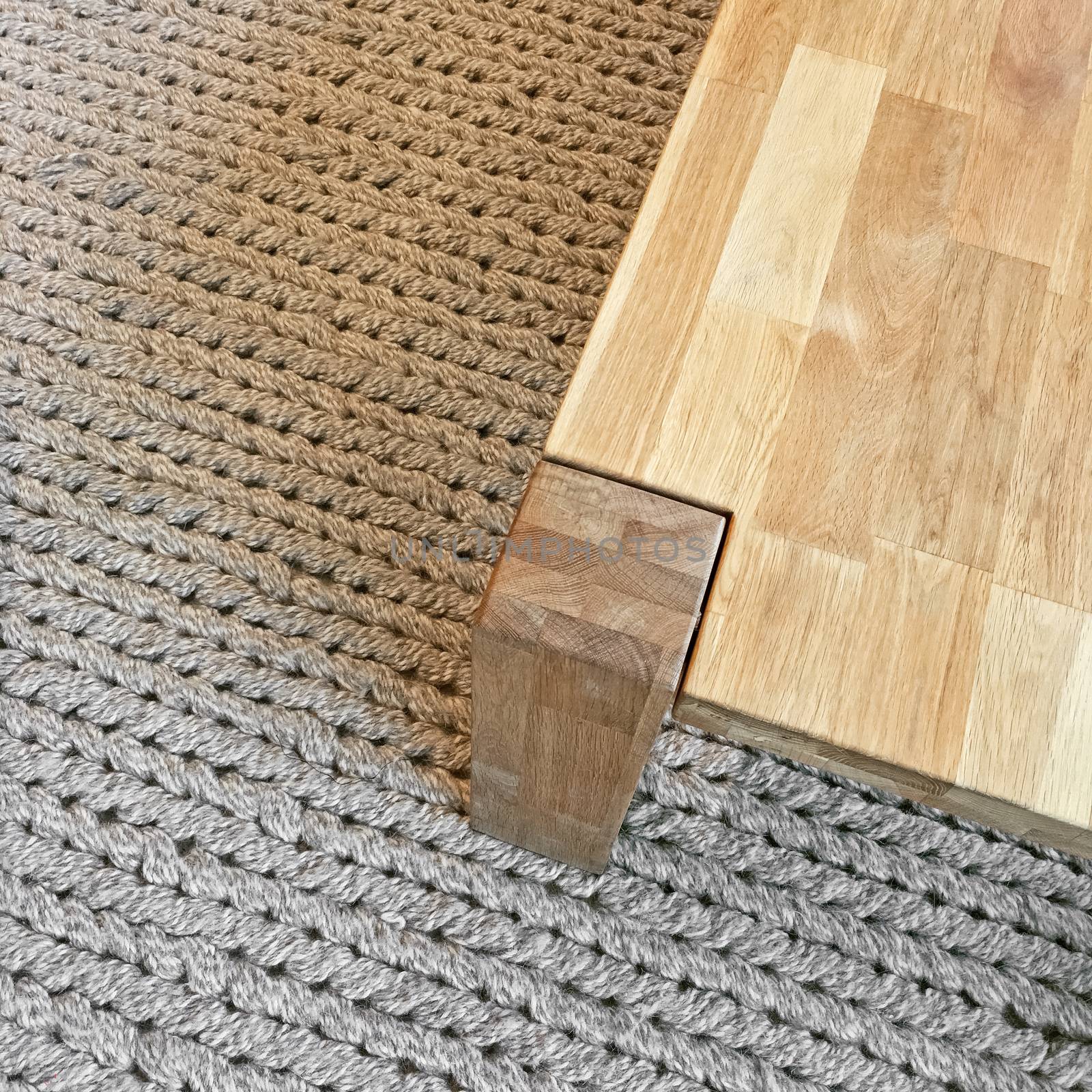 Wooden table on gray knitted carpet. Modern design.