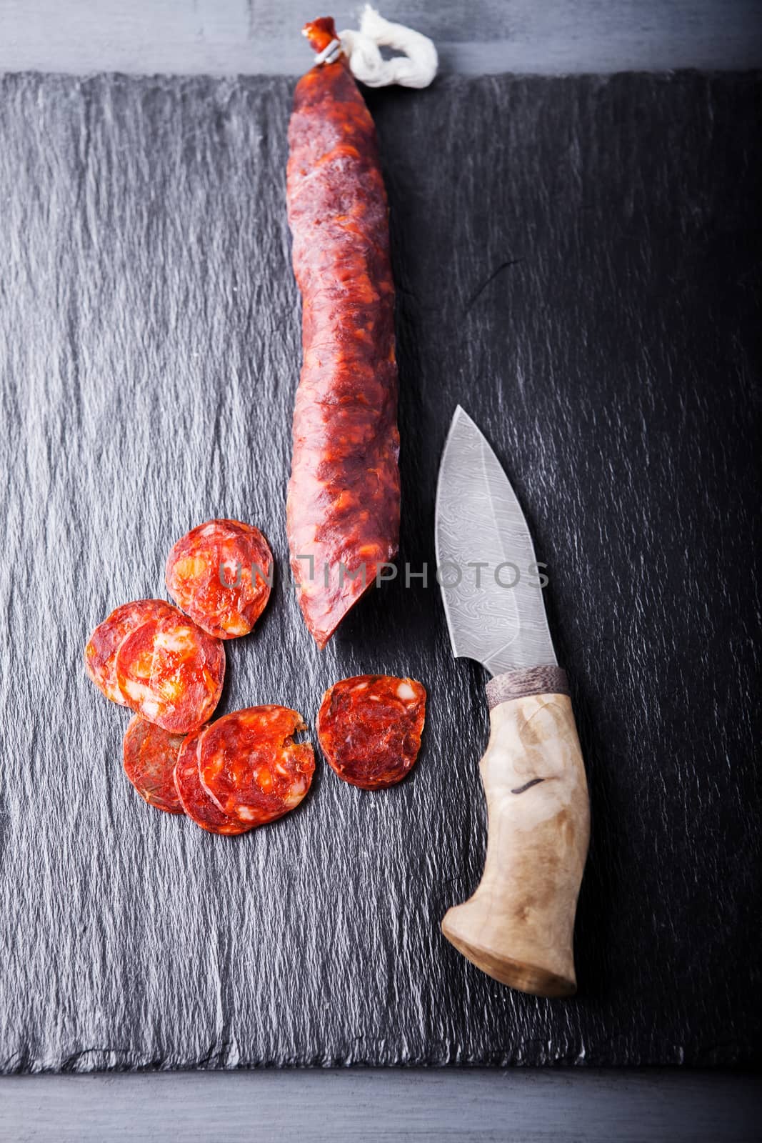 Spanish chorizo and a knife on a stone plate