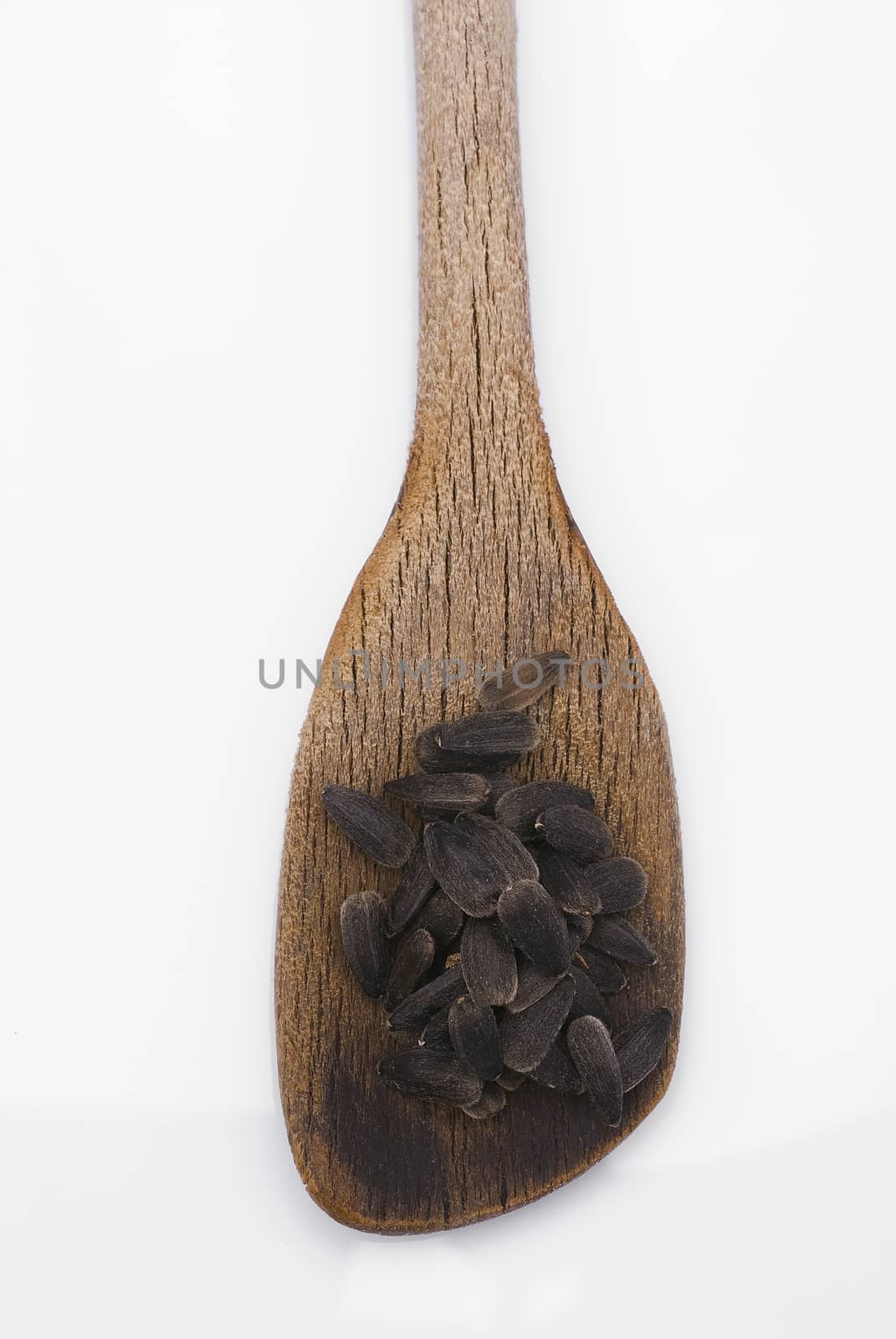 Sunflower seeds with wooden spoon isolated on white background.