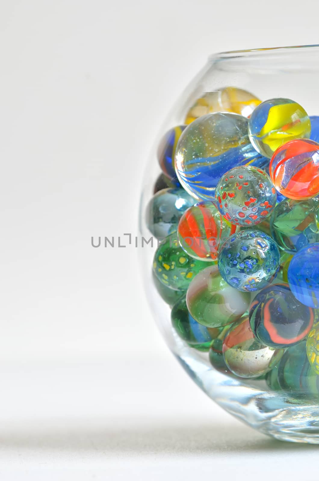 glass marbles in transparent bowl on white table