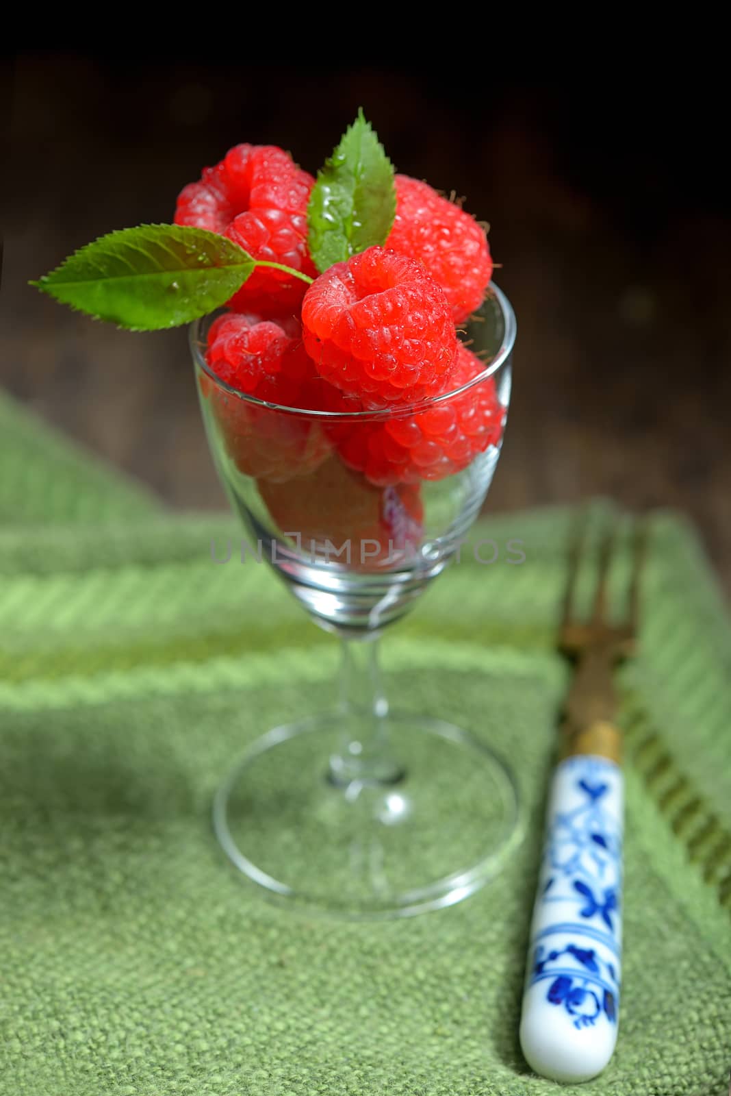 Raspberries in small glass on wooden table