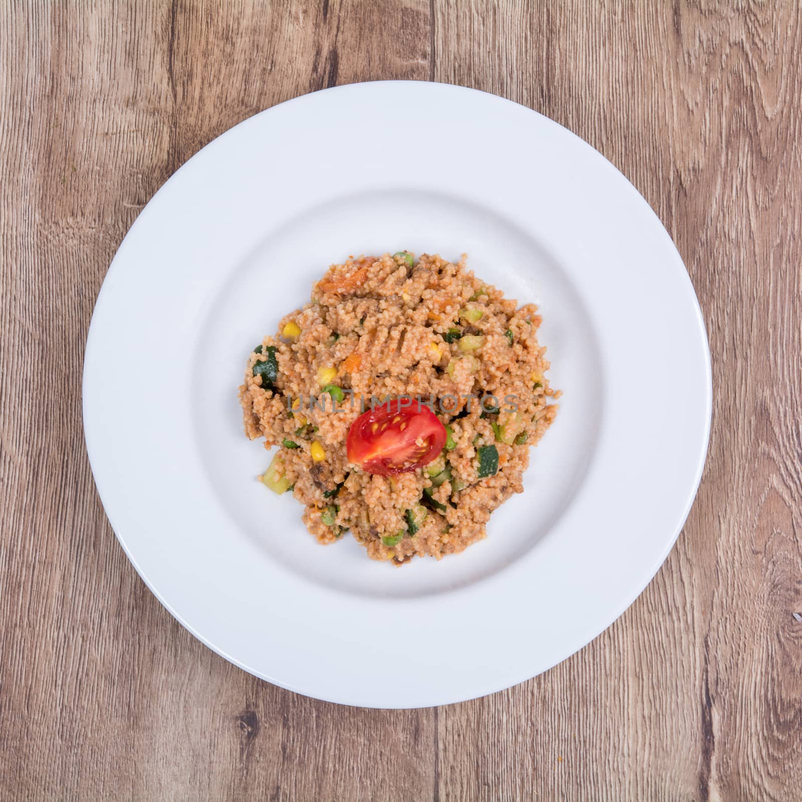 Vegetarian food on a white plate with wooden background