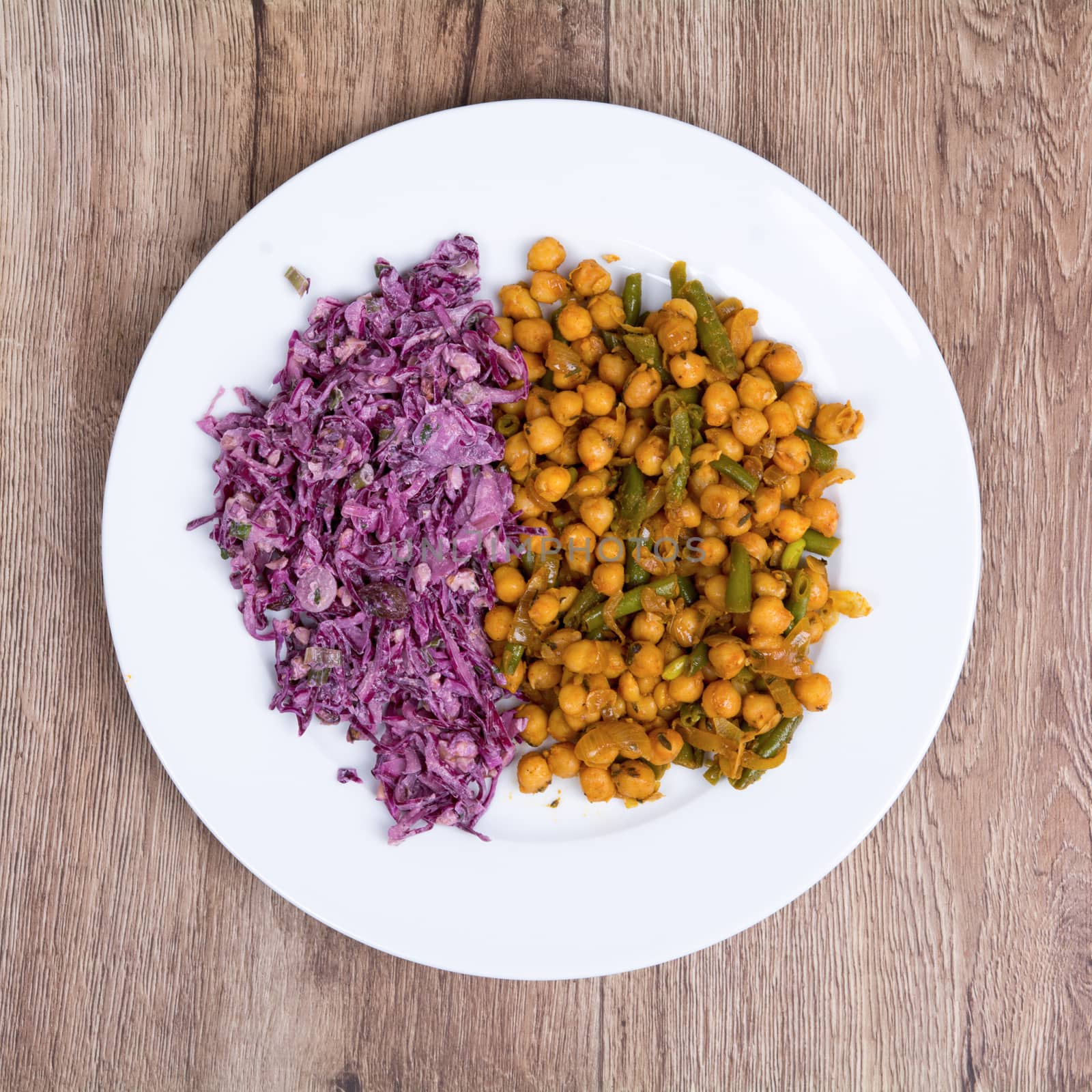 Vegetarian food on a white plate with wooden background