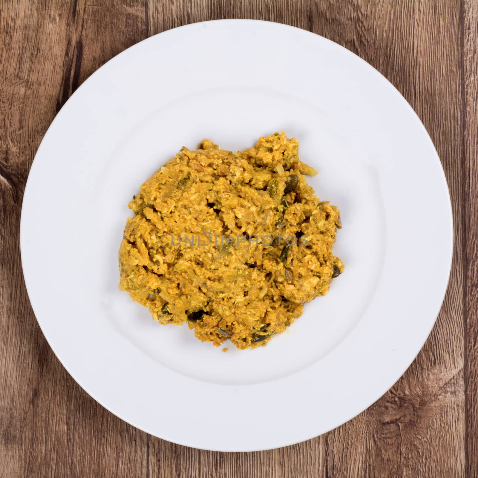 Vegetarian food on a white plate with wooden background