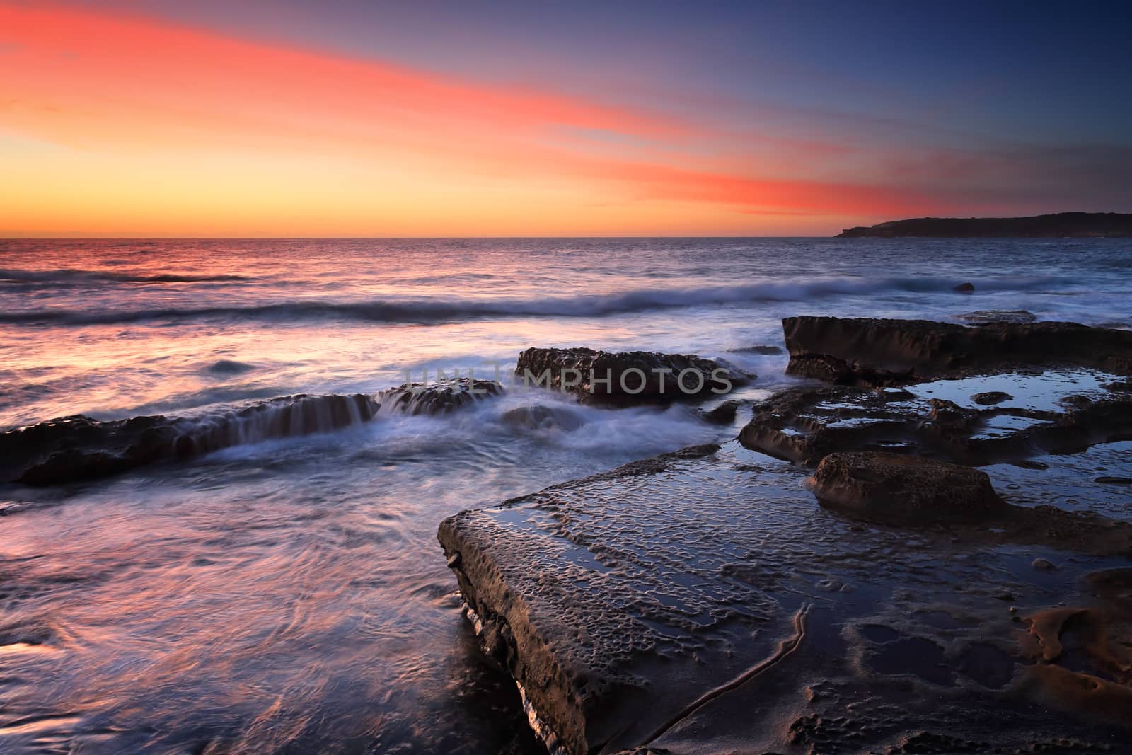 Beautiful sunrise over the ocean and waves wash over rocks.  Location - Maroubra Australia