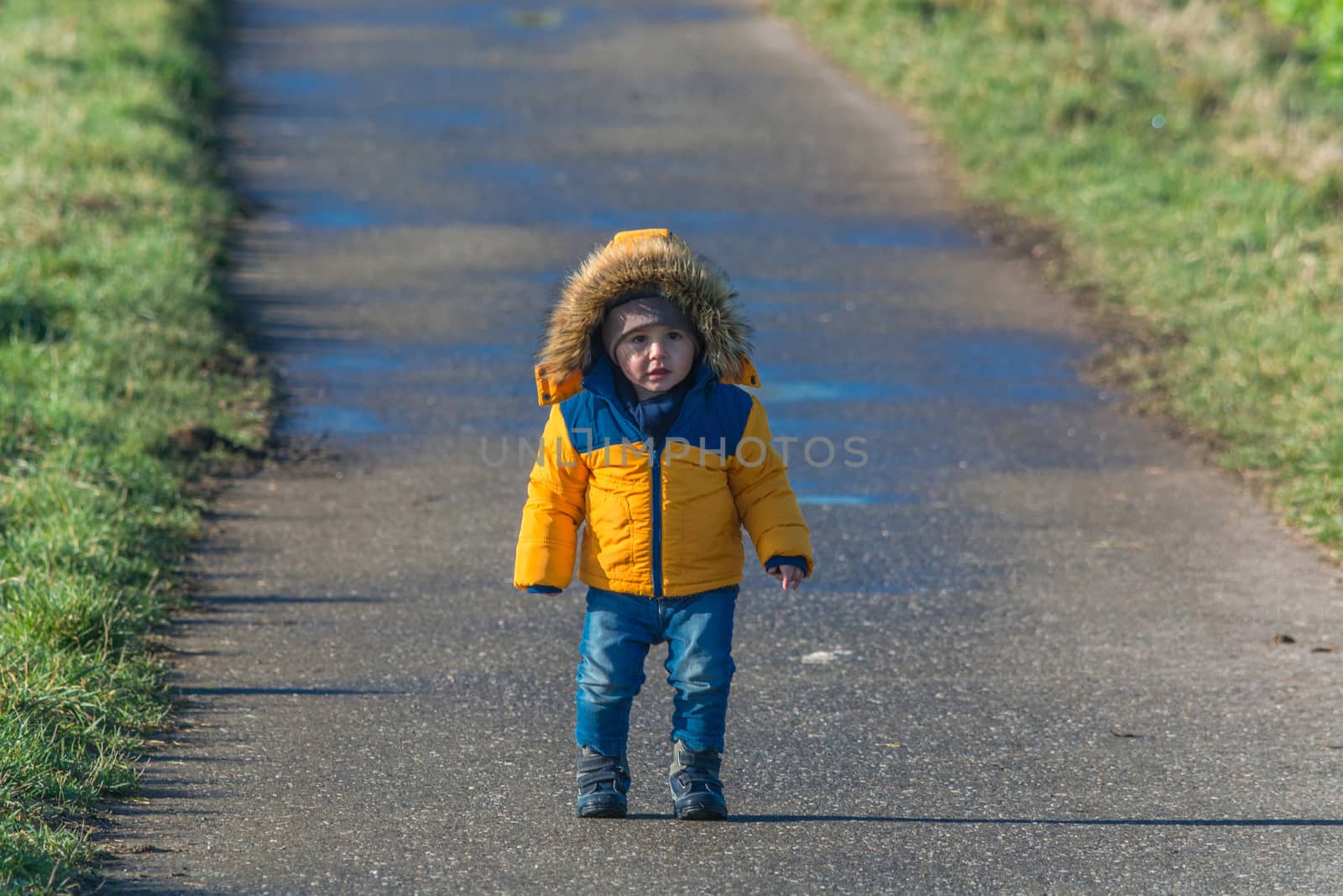 Little boy is laughing and walking on a country road.