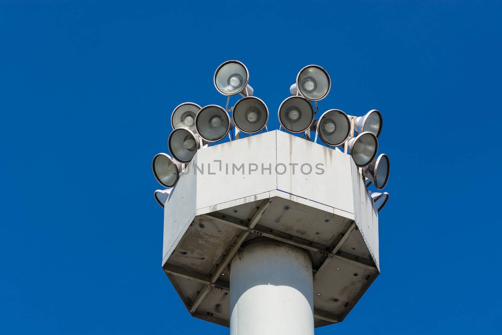 Many speakers on a high tower against a clear sky background.