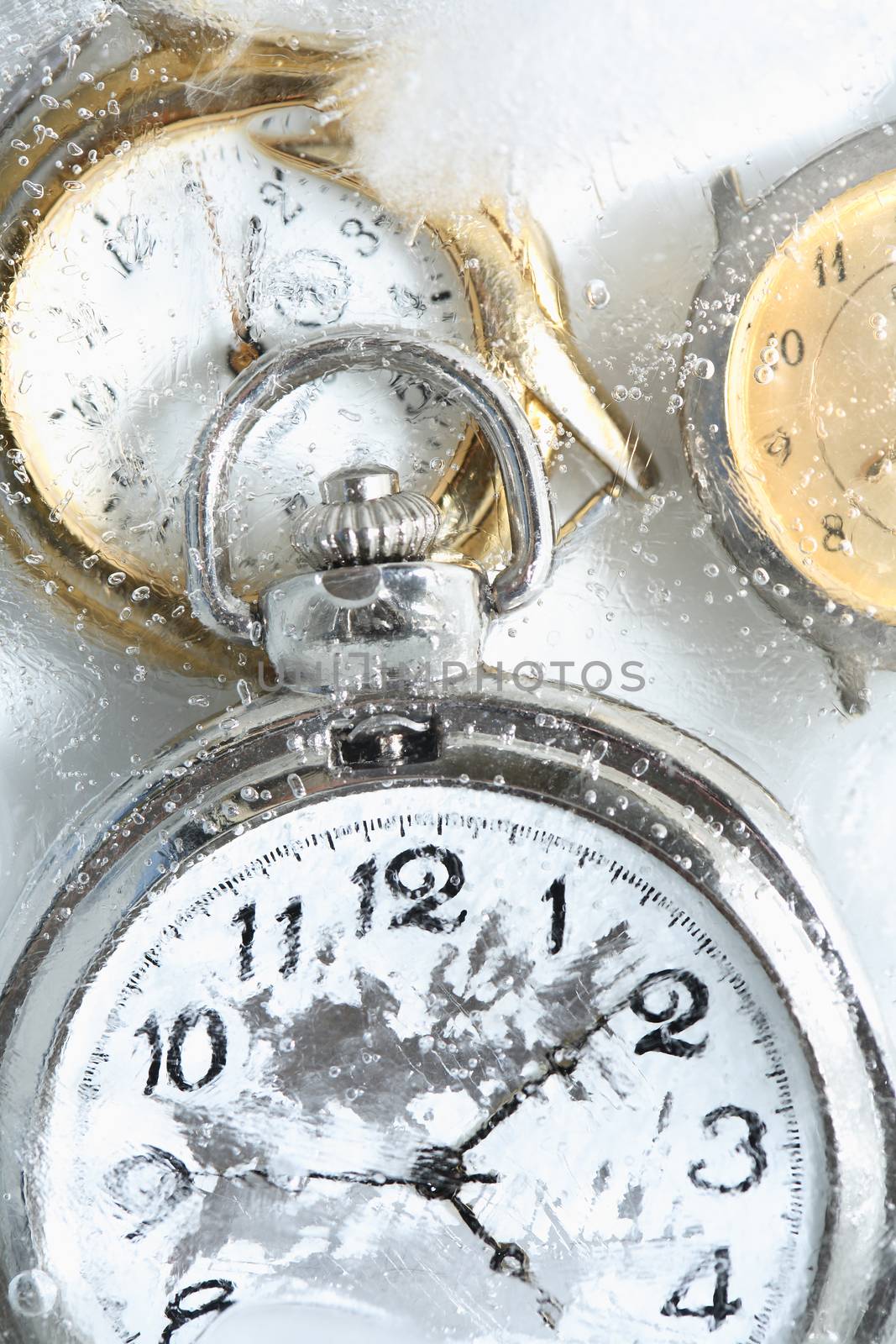 Permafrost concept. Closeup of pocket watch under frozen water surface with ice