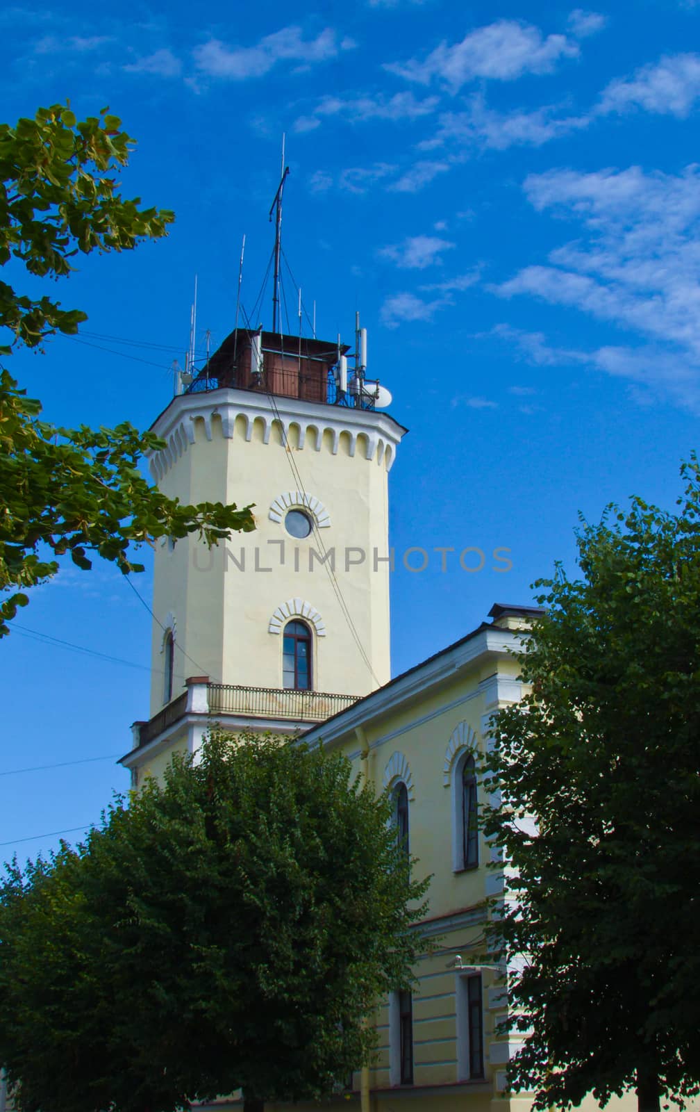 building with a tower in the center of the city on a background of blue sky
