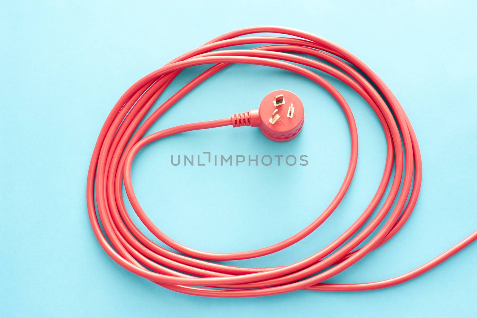 Coiled red electrical cable or lead with plug by stockarch