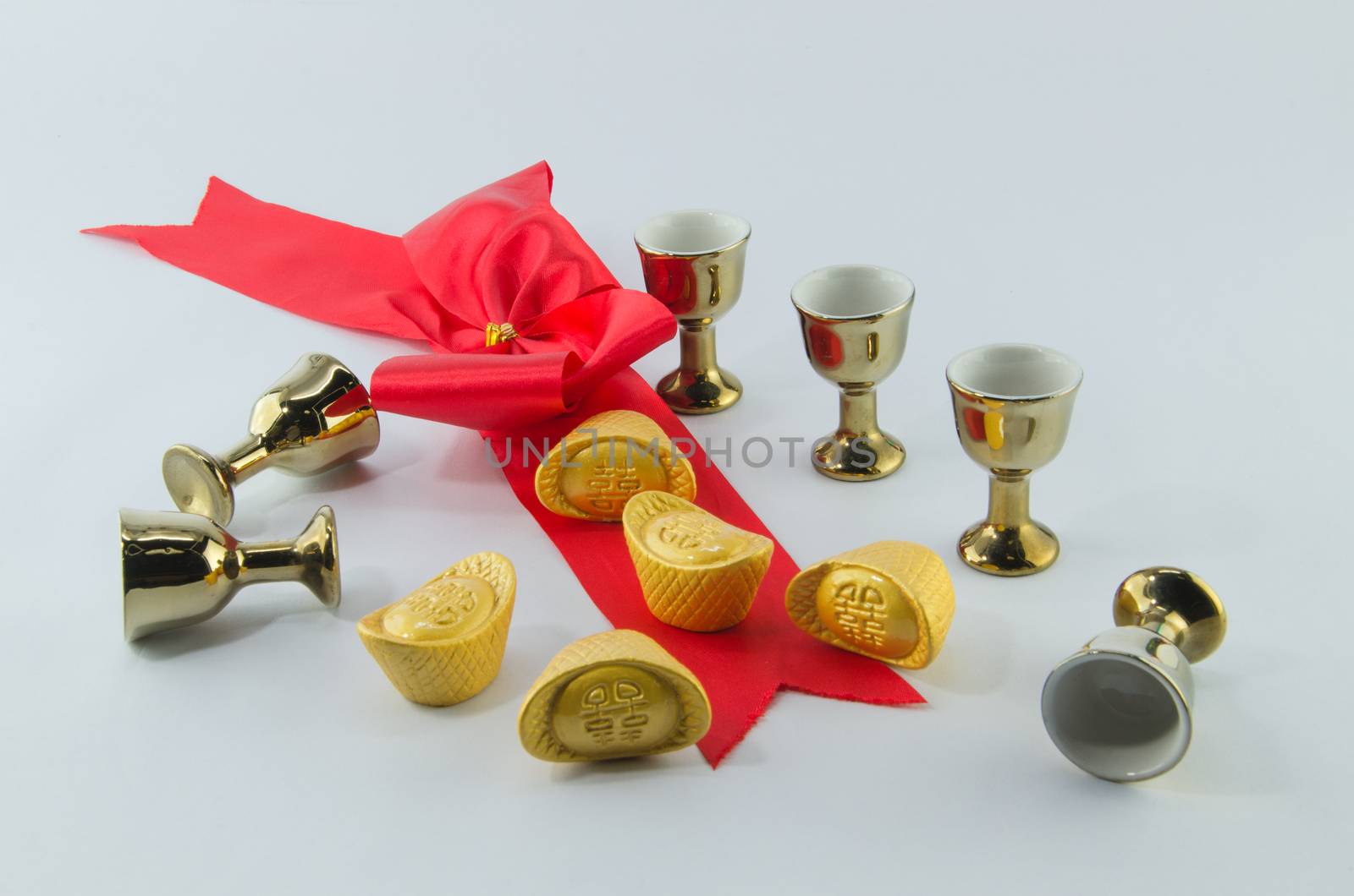 Gold ingot Red ribbon bow Gold jug Tea glass on white background.