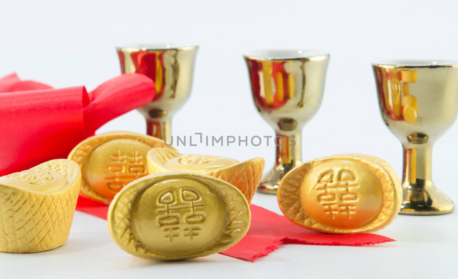 Gold ingot Red ribbon bow Gold jug Tea glass on white background.