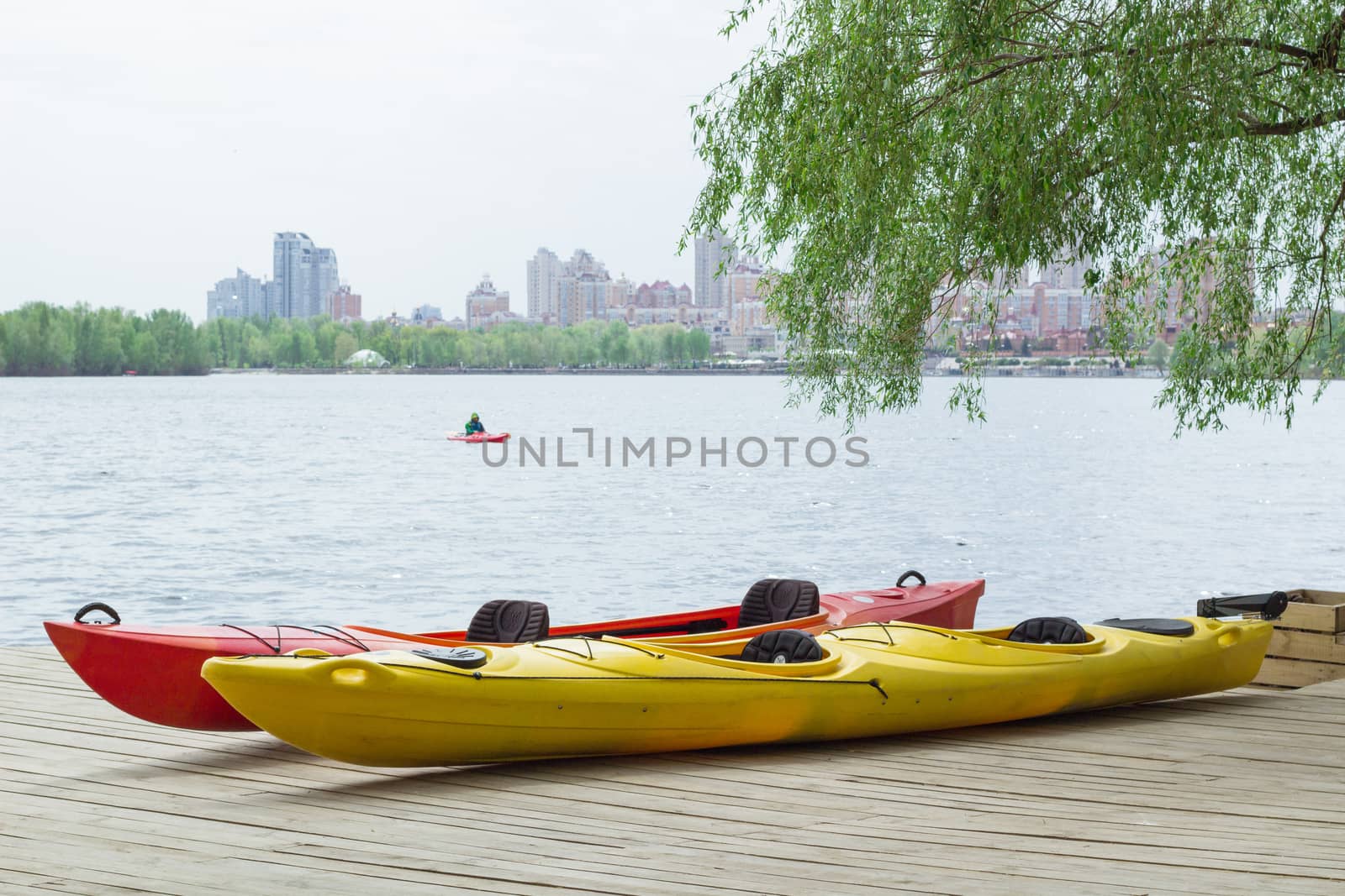Two kayak boats on wooden deck at kayak station near river bank