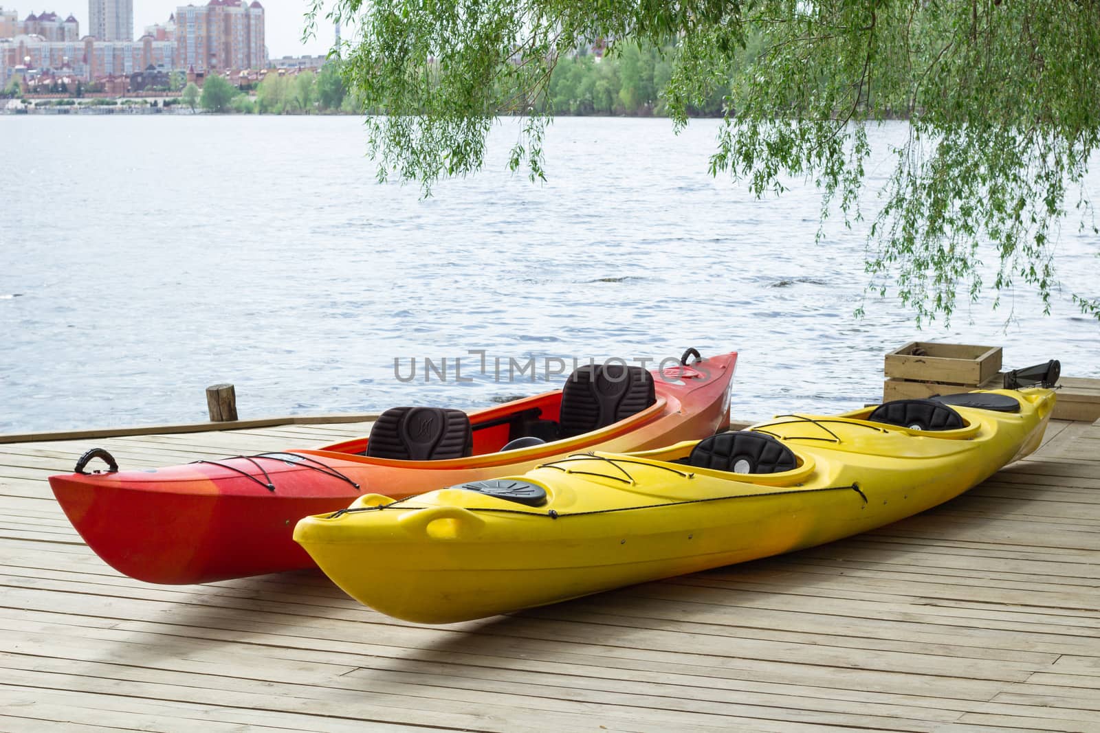 Two kayak boats on wooden deck at kayak station near river bank