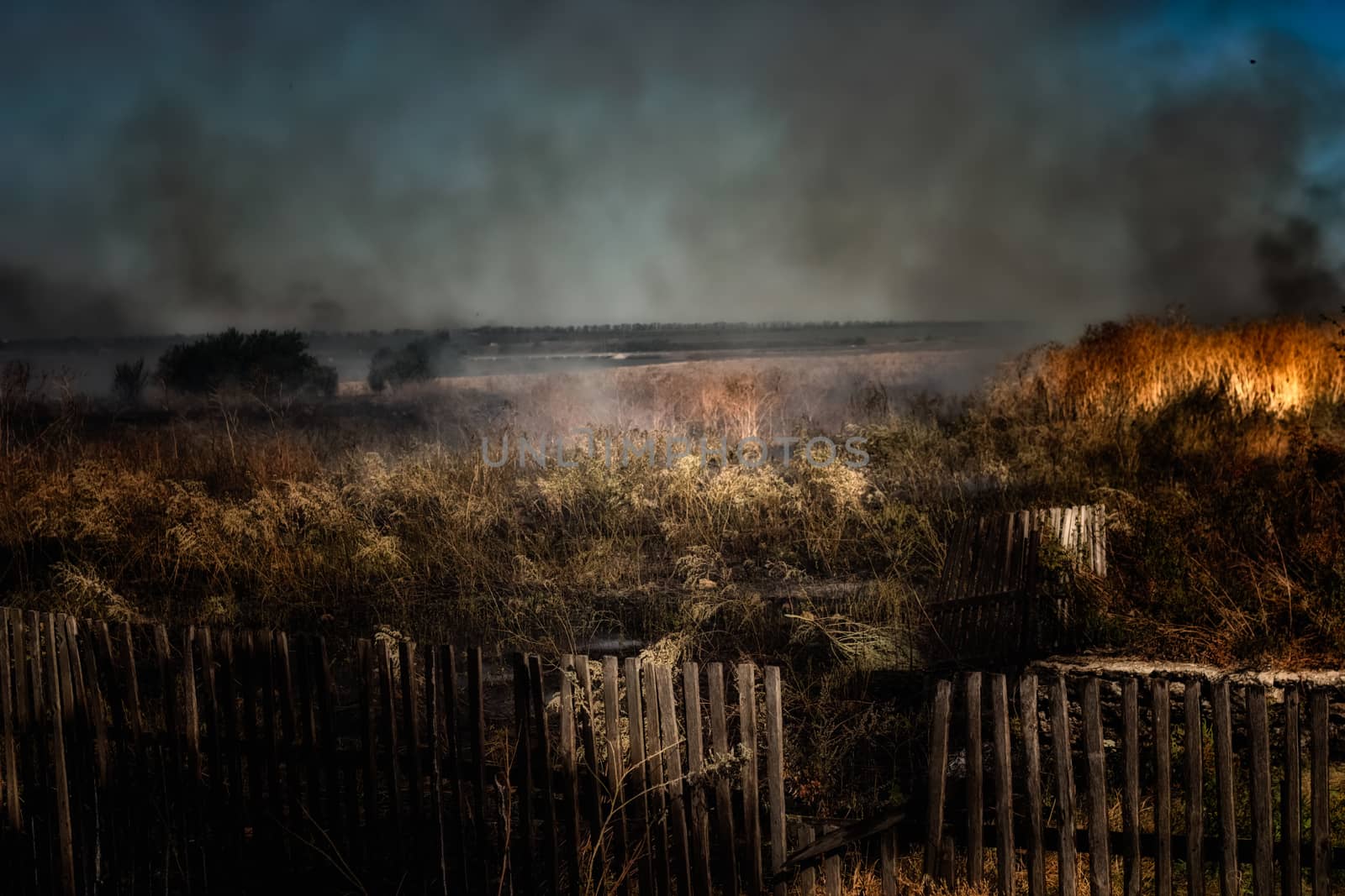 Ground fire - burning grass in the steppe. Dark, gloomy landscape. Clubs of smoke in the sky. Accident, man-caused disaster.